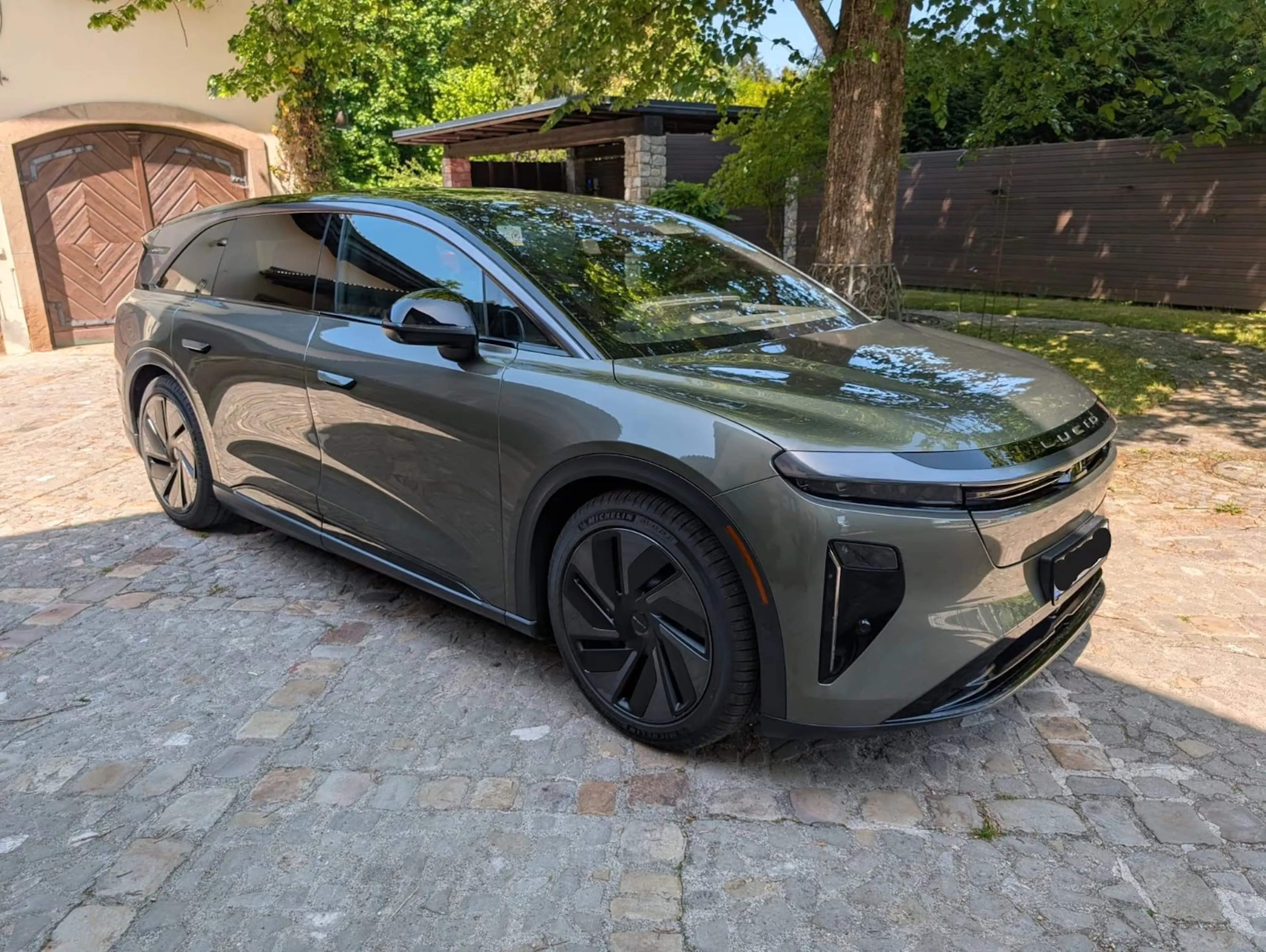 Grauer Lucid Gravity steht in einer Einfahrt vor einer Garage.