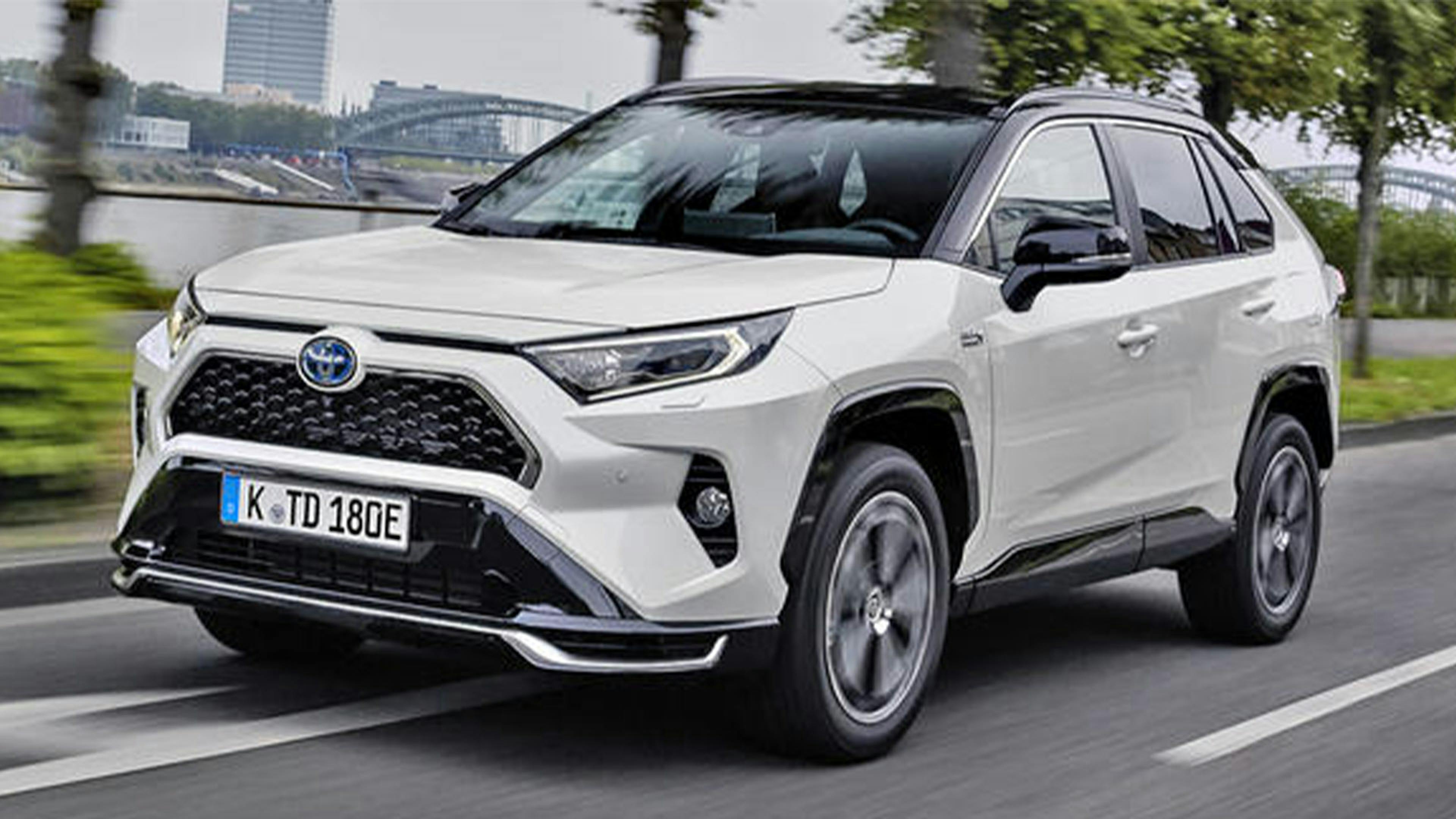 Ein weißer Toyota RAV-4 fährt durch eine urbane Kulisse