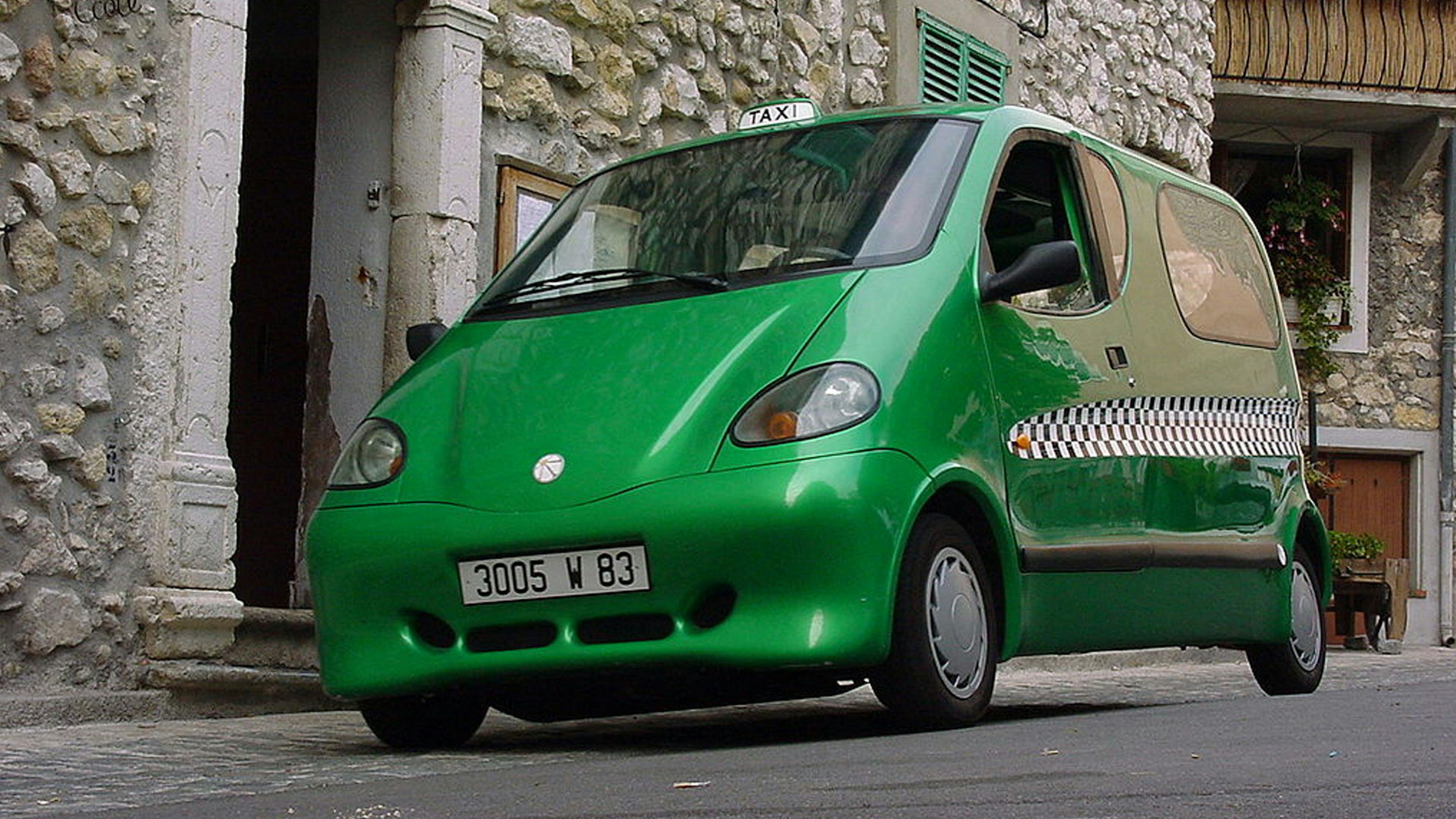 Eine grüne OneCat Autostudie steht vor einem Haus.