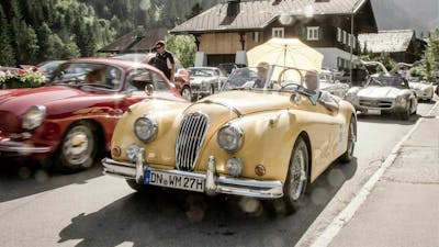 Zwei ältere Herren sitzen in einem gelben Oldtimer mit H-Kennzeichen