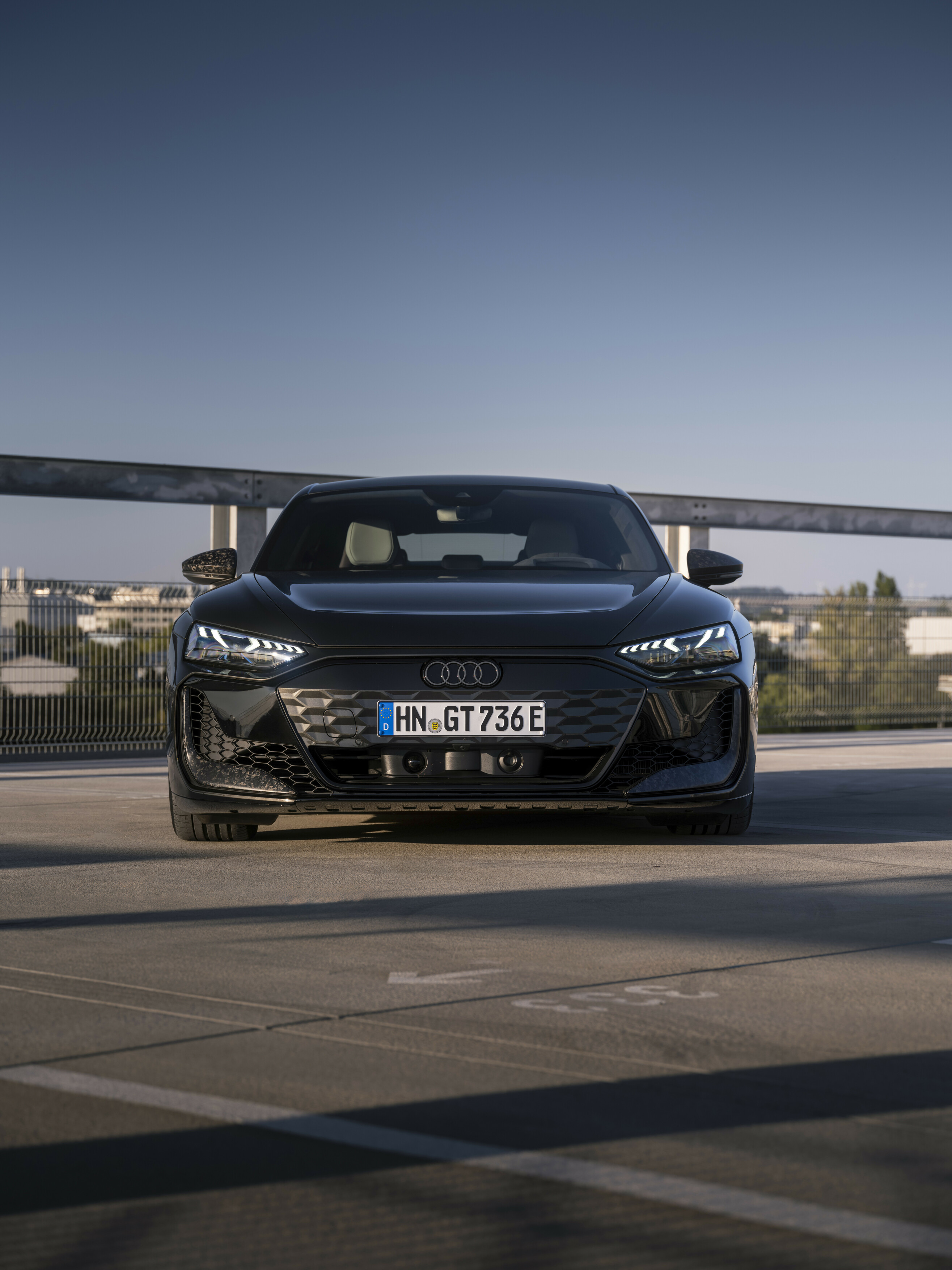 Audi RS e-tron GT performance in Schwarz, Frontansicht auf einem Parkdeck bei Abenddämmerung.