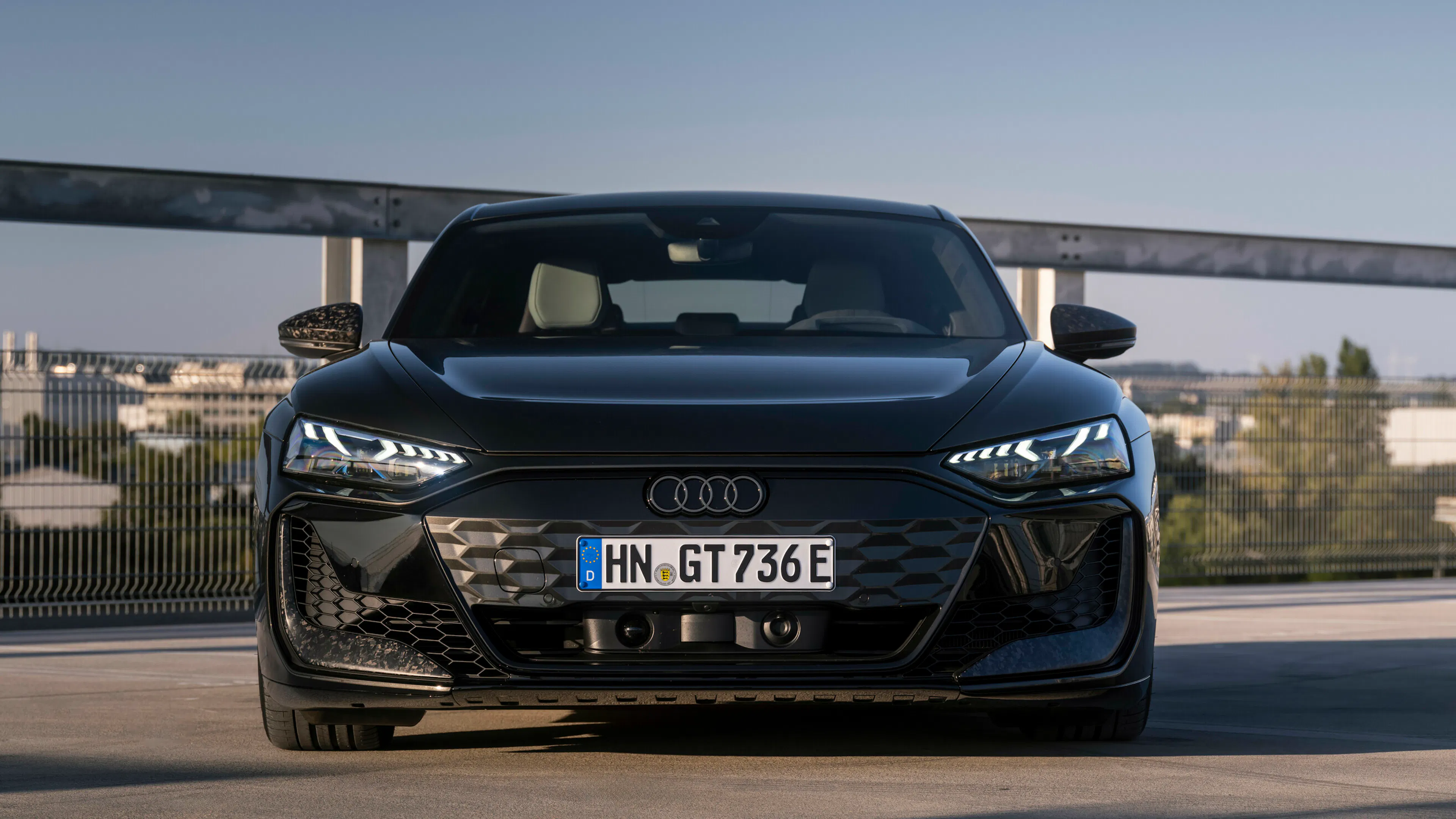 Audi RS e-tron GT performance in Schwarz, Frontansicht auf einem Parkdeck bei Abenddämmerung.