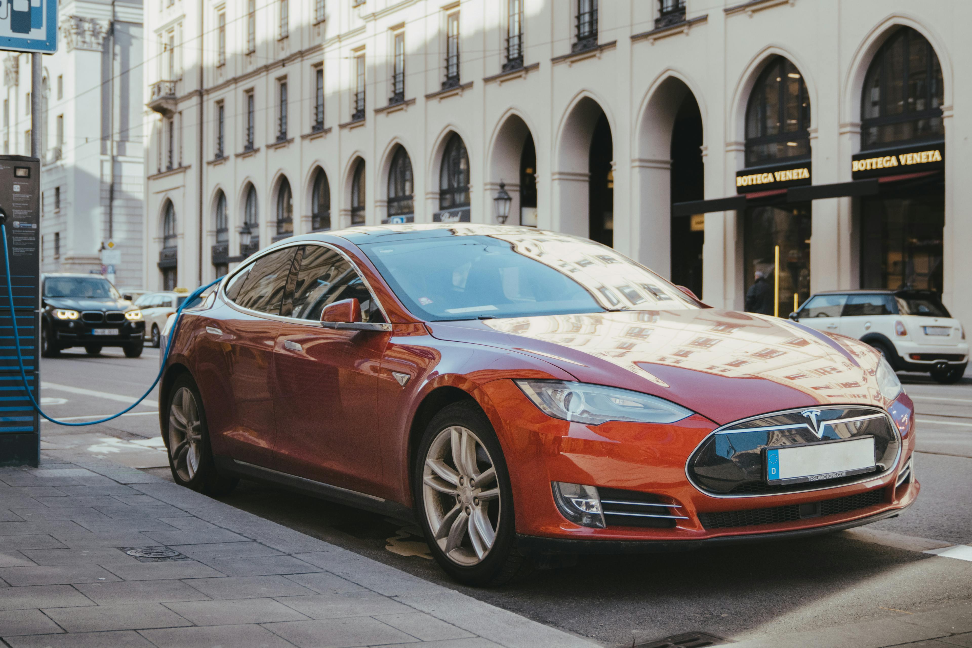 Ein rotes Tesla Model S lädt an einer öffentlichen Ladesäule.