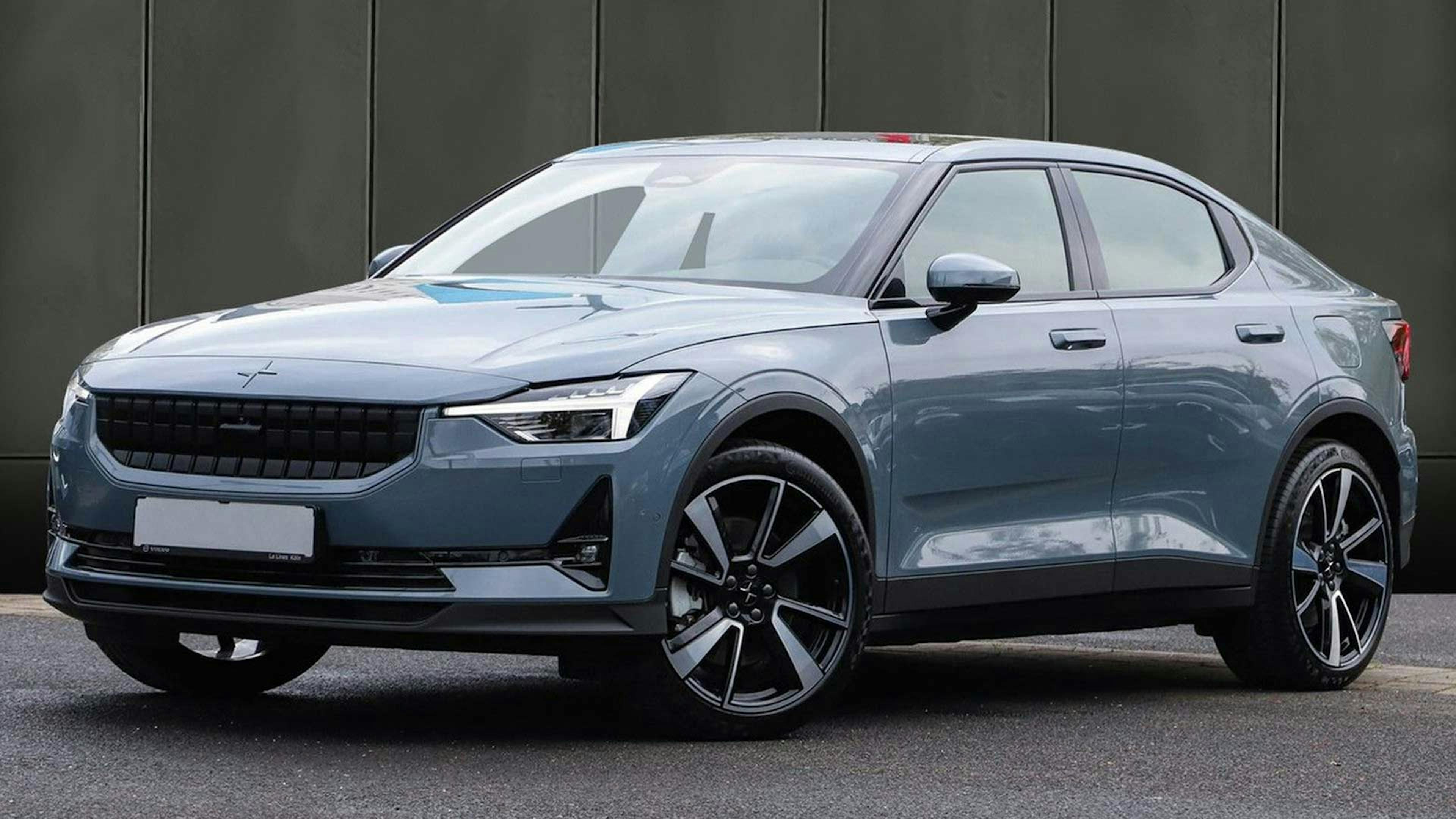 Ein graues Polestar-2-Elektroauto mit Allradantrieb steht vor einer dunklen Wand.