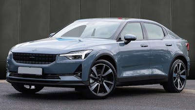 Ein graues Polestar-2-Elektroauto mit Allradantrieb steht vor einer dunklen Wand.