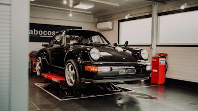 Ein schwarzer Porsche steht auf einer Hebebühne in einer Autowerkstatt