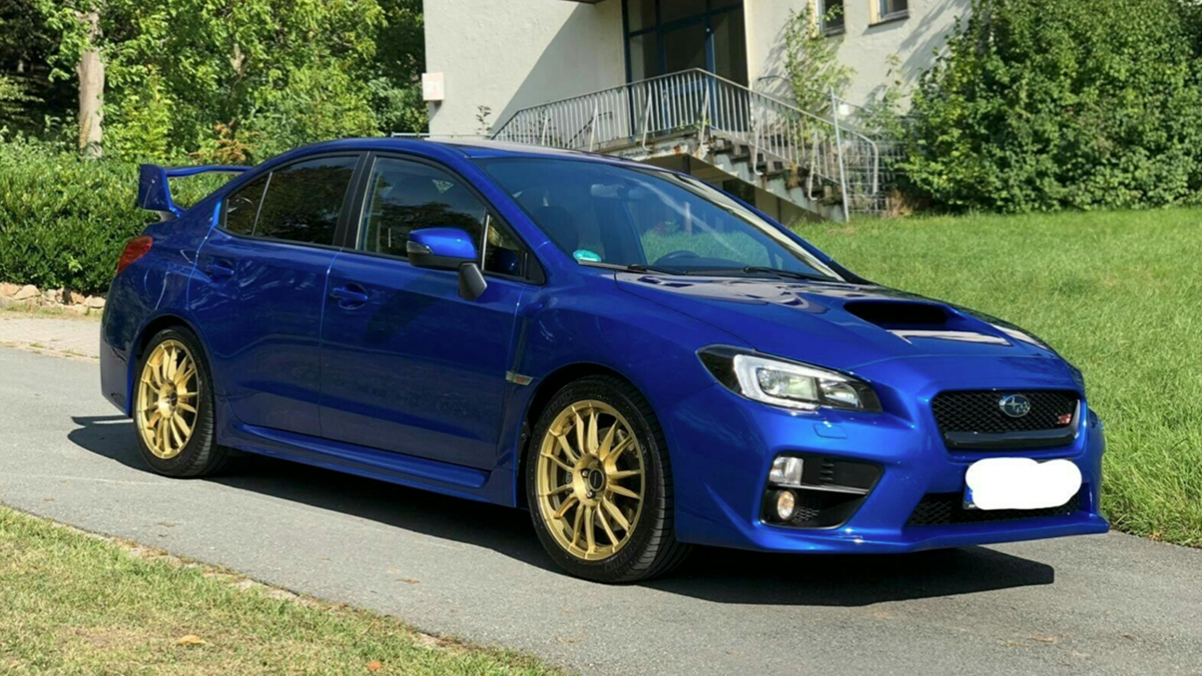 Ein blauer Subaru Impreza WRX STI steht vor einem hellen Gebäude