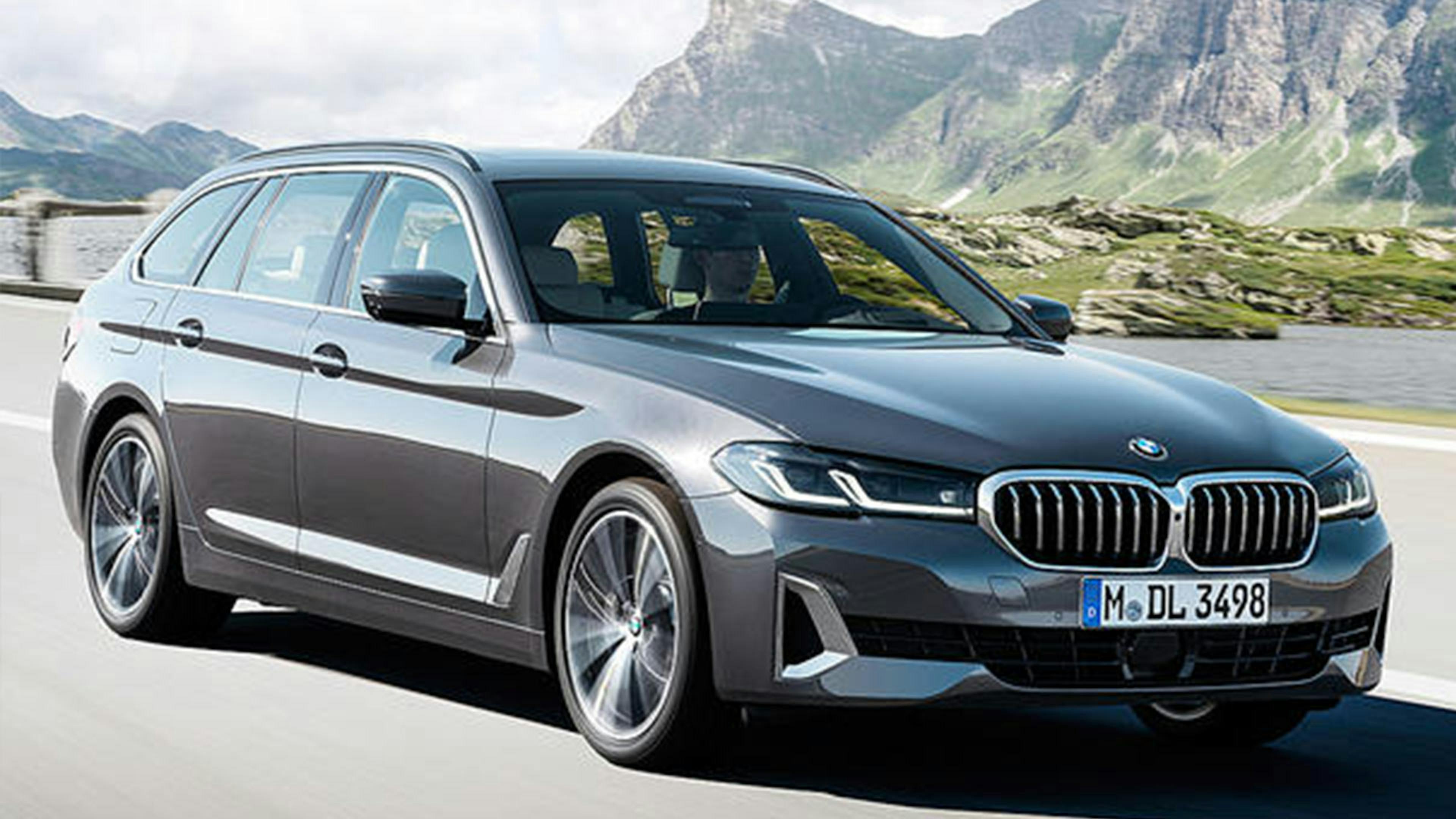 Ein schwarzer BMW 5er Touring fährt eine Bergstraße entlang.