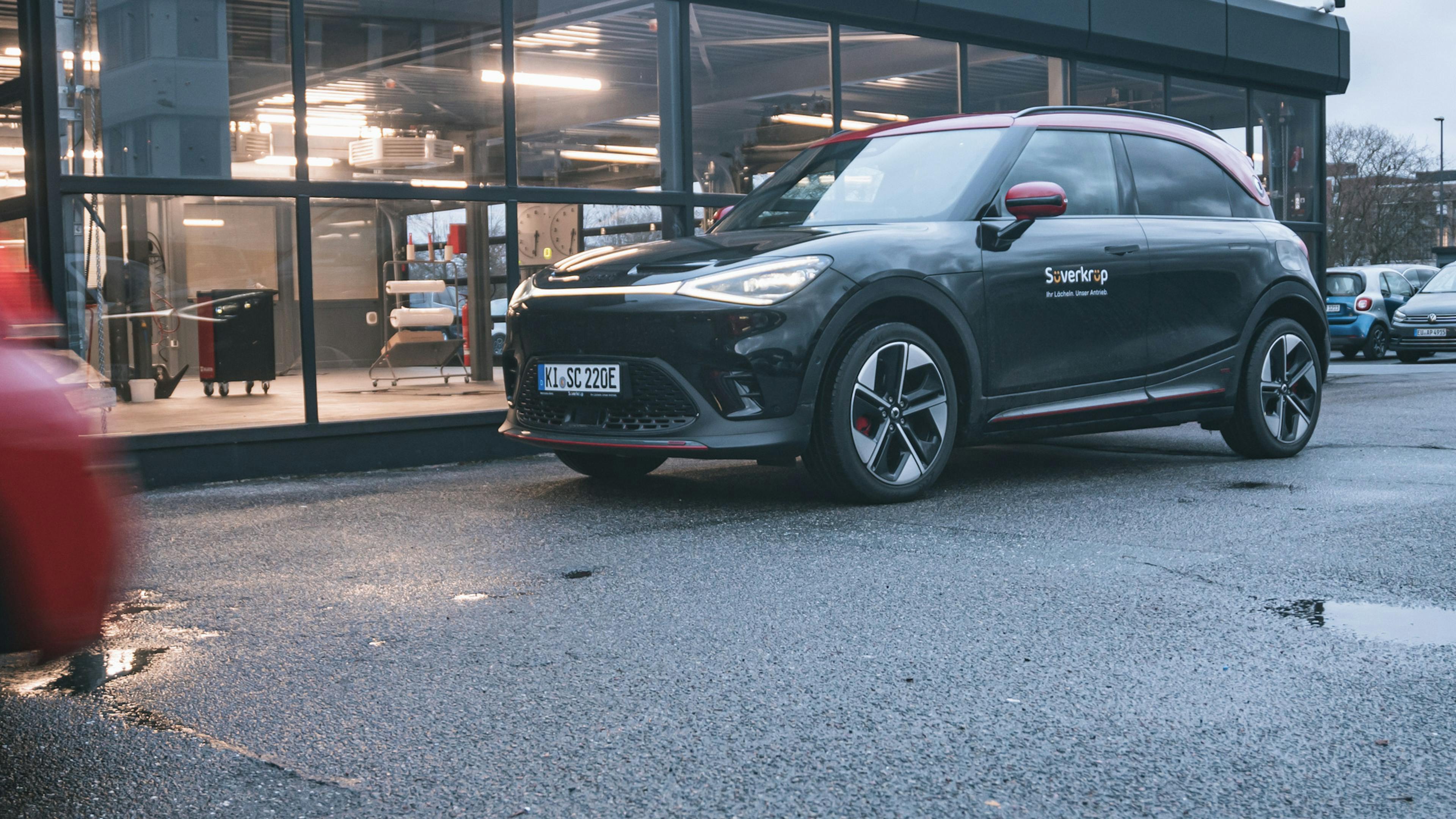 Ein Smart #1 Brabus steht vor einer beleuchteten Halle.