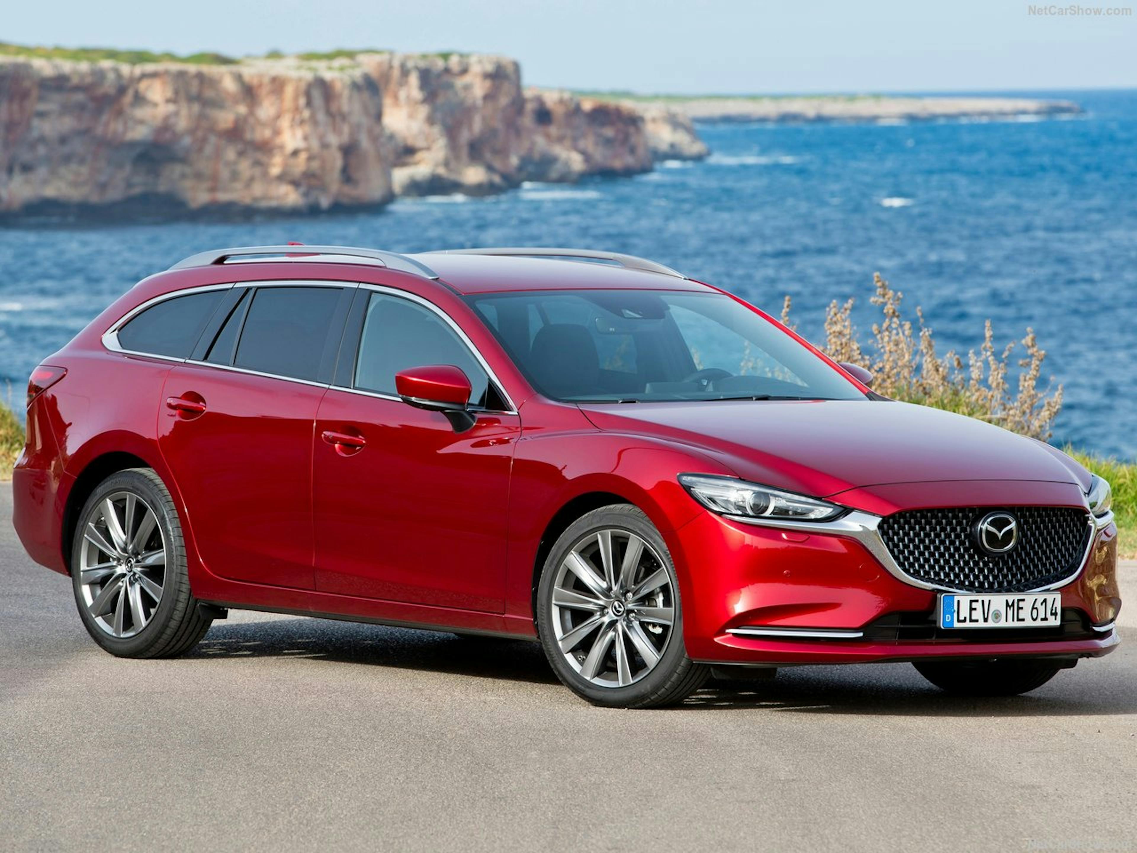 Ein roter Mazda6 steht an vor einem Küsten-Hintergrund. 