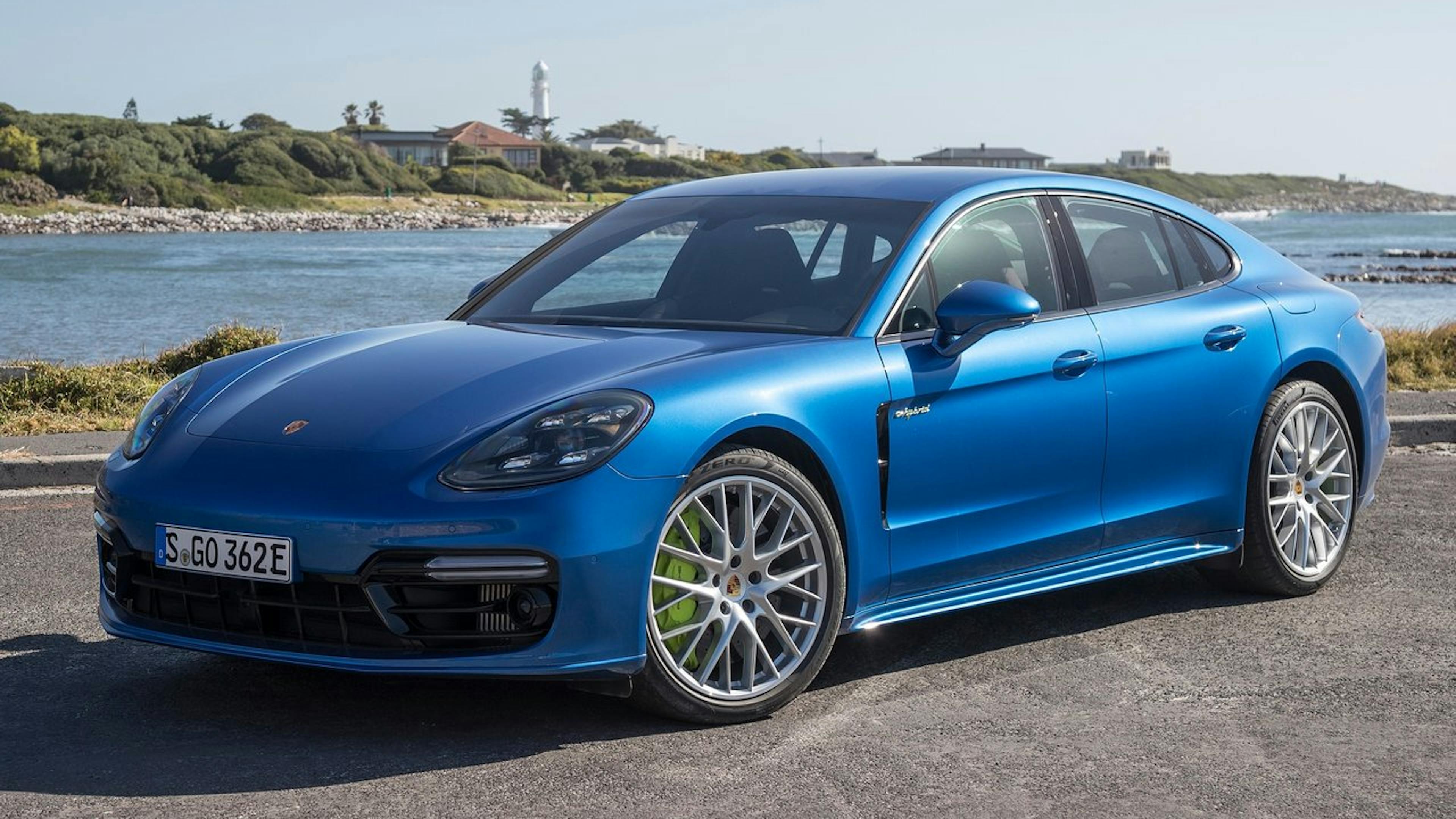 A blue Porsche Panamera is parked on a shore.