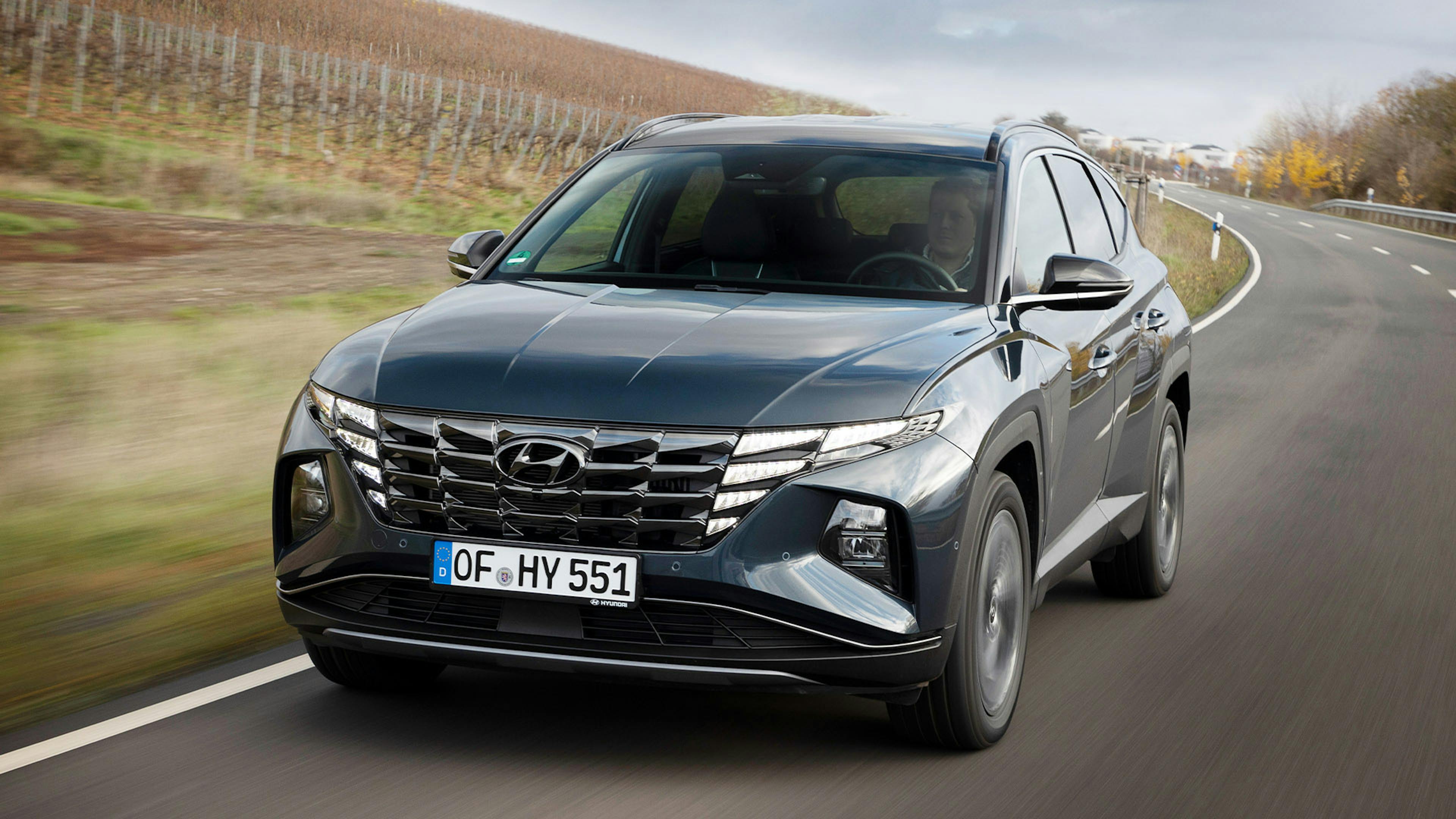 Ein schwarzer Hyundai Tucson fährt an einem Weinberg vorbei