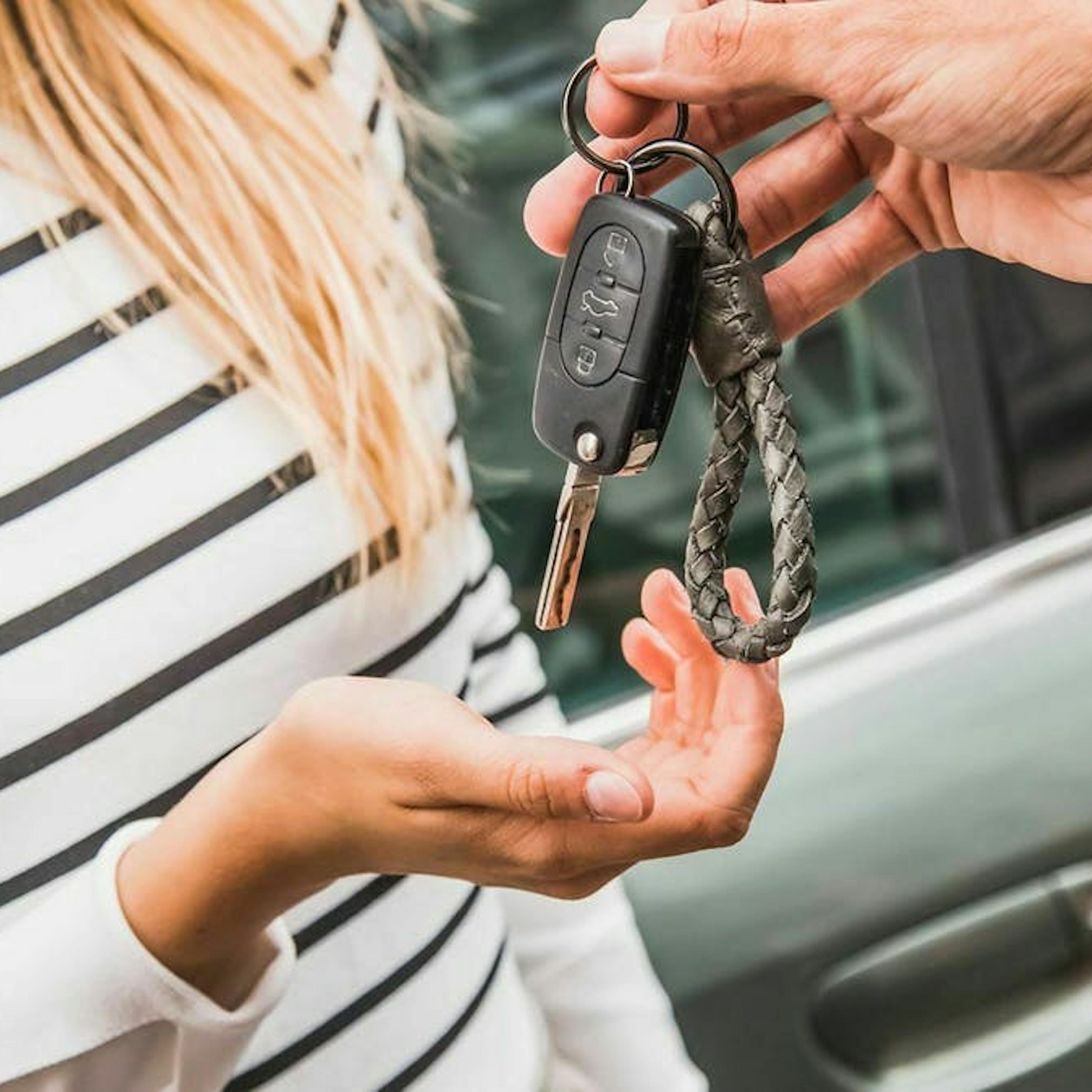 Ein Mann überreicht einer blonden Frau einen Autoschlüssel.
