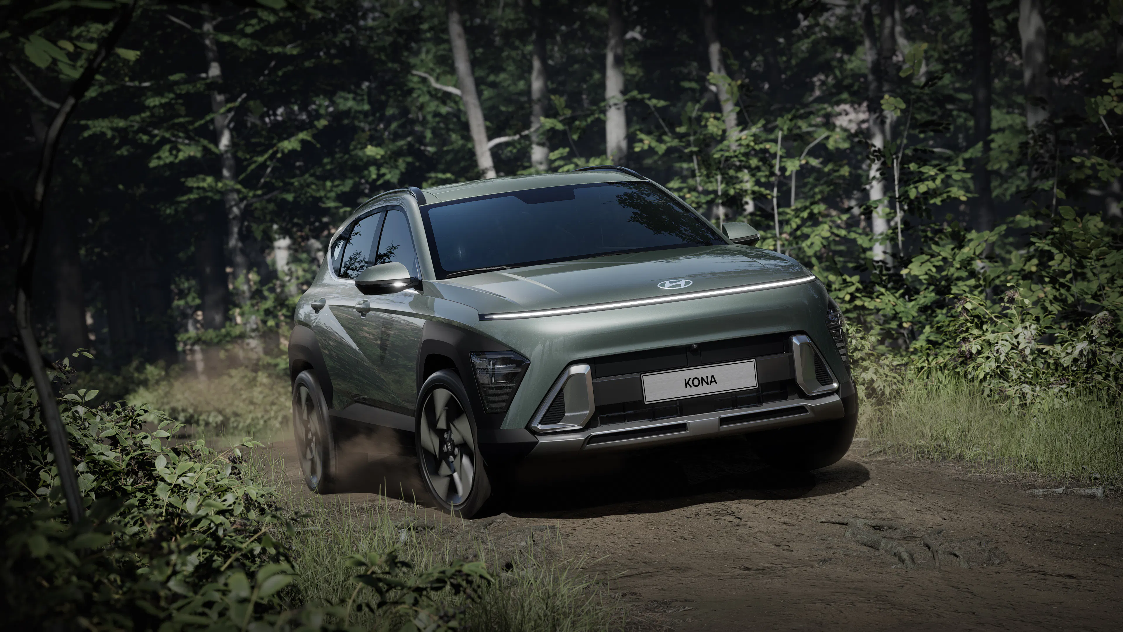 Grau-grüner Hyundai Kona mit durchgehendem Lichtband an der Front auf einem Waldweg.