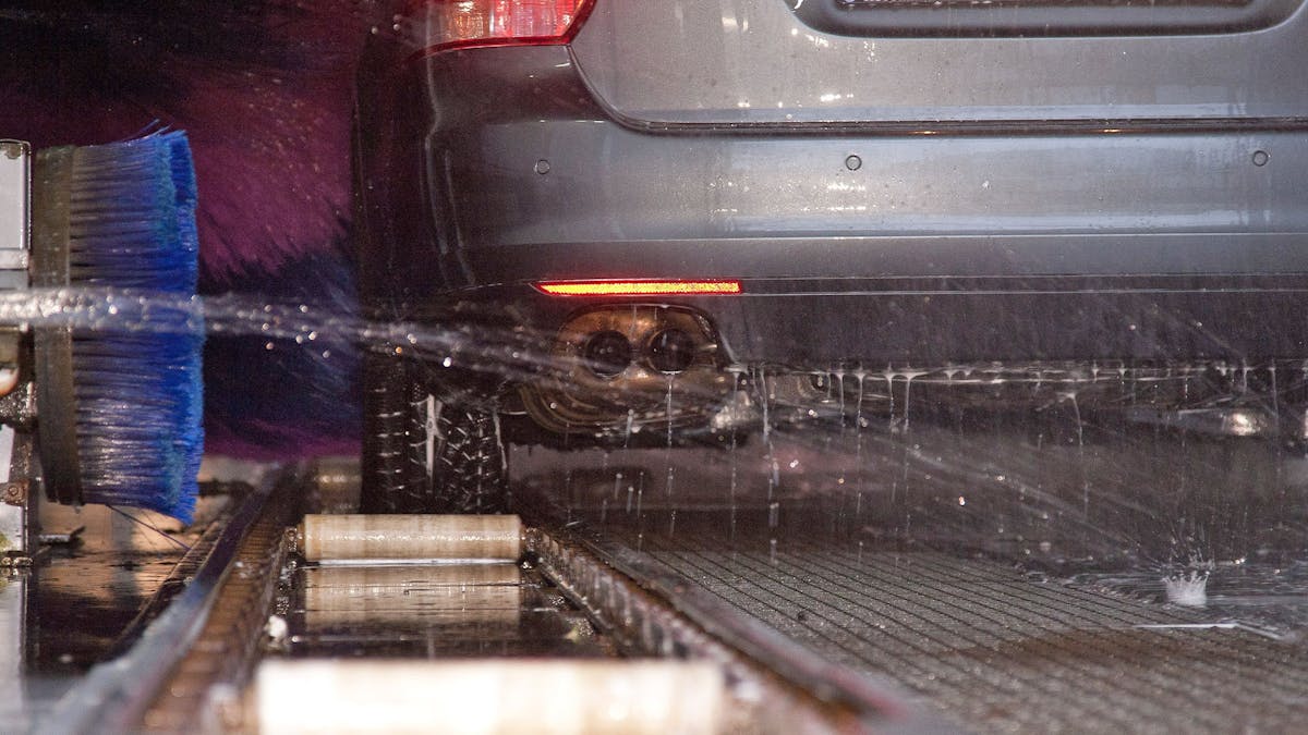 Ein Auto steht in einer Waschstraße, während es eine Unterbodenwäsche erhält.