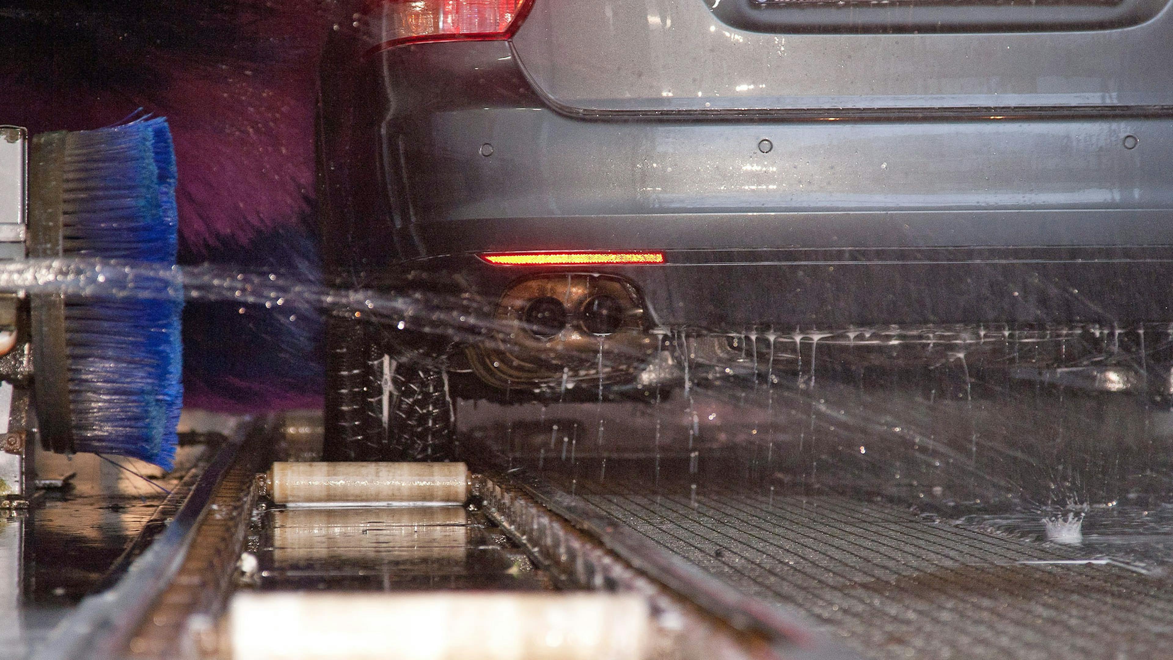 Ein Auto steht in einer Waschstraße, während es eine Unterbodenwäsche erhält.