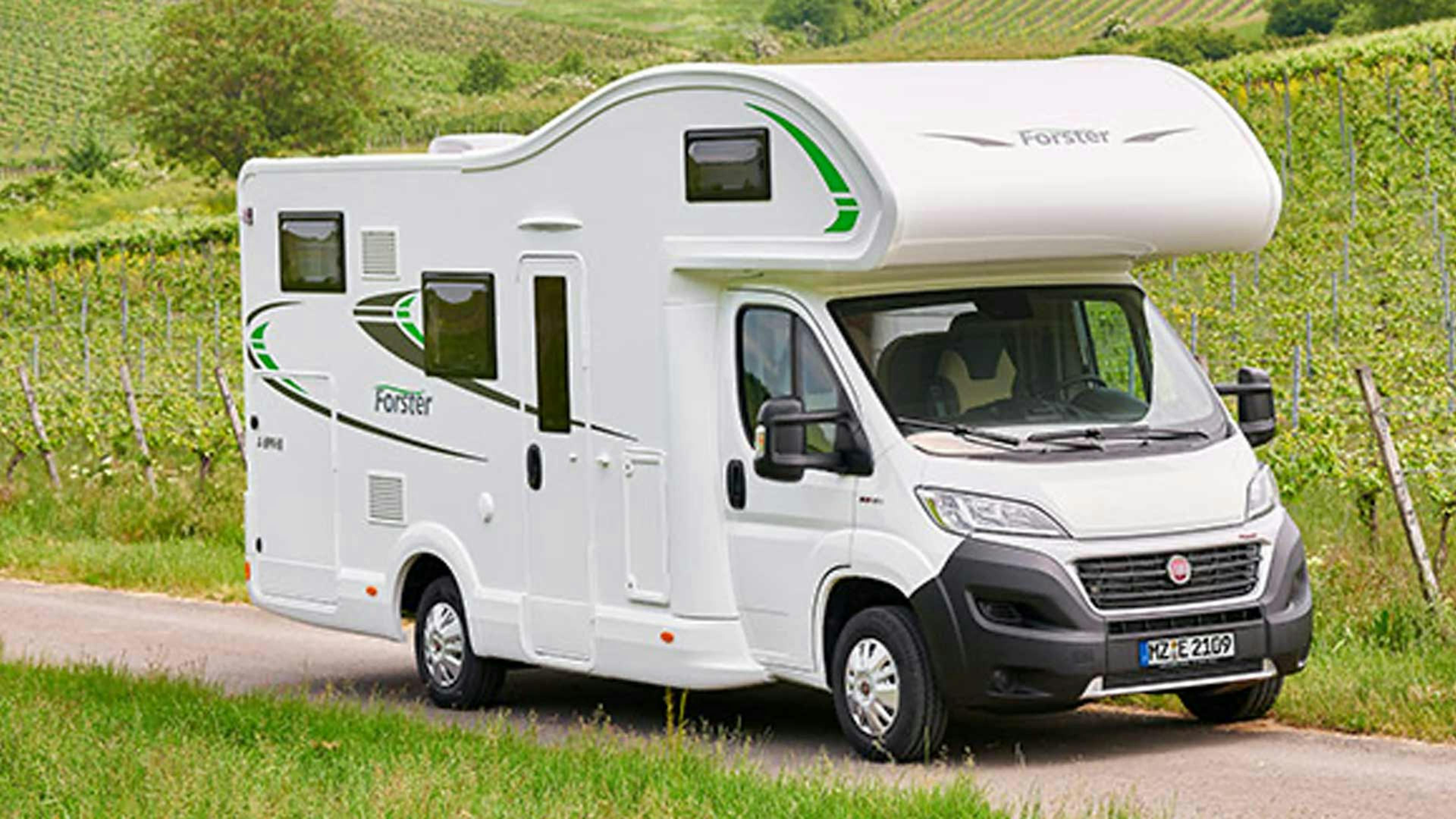 Ein Forster A699 EB Wohnmobil mit Alkoven steht an einem Weinberg.