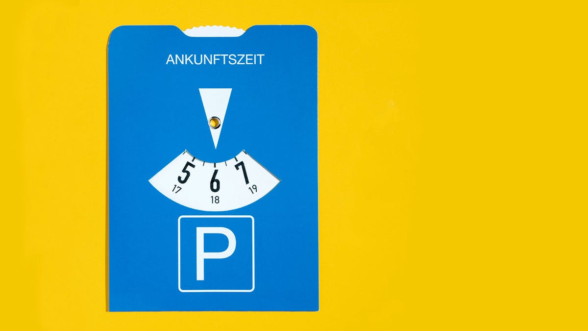 Eine blaue Parkscheibe vor gelbem Hintergrund.
