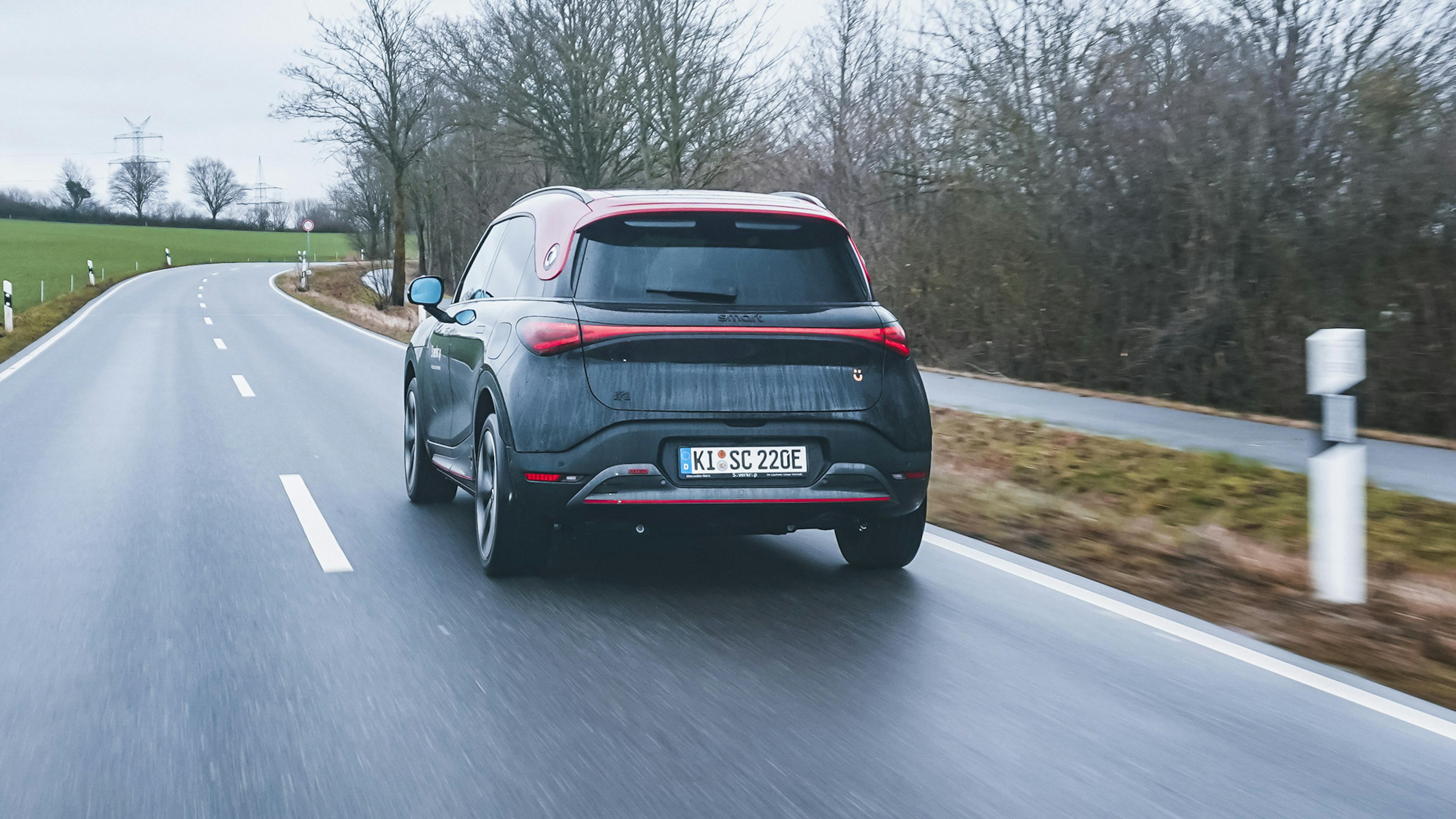 Ein schwarz-roter Smart #1 Brabus fährt über eine Landstraße.