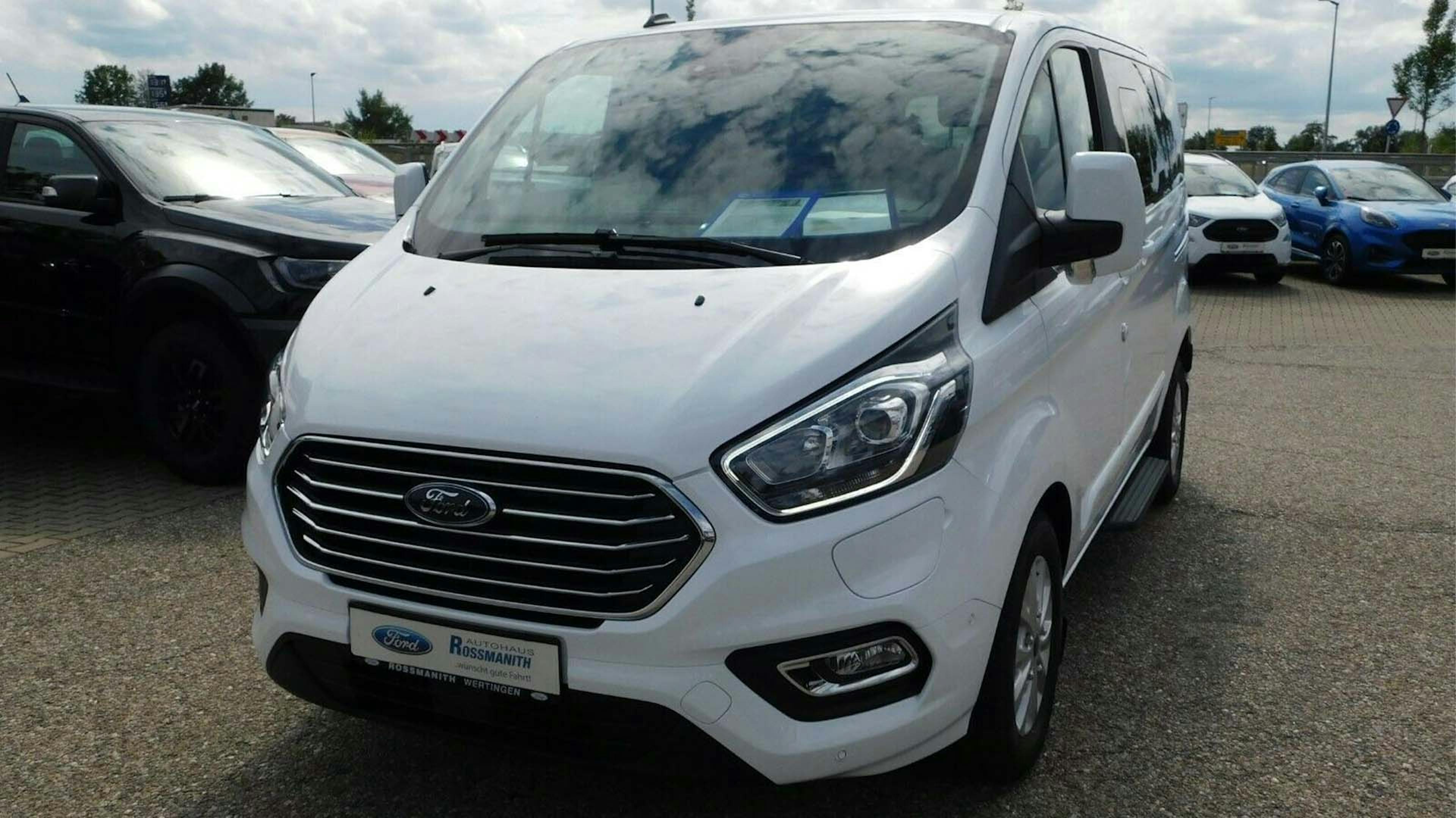 Ein weißer Ford Tourneo Custom Plug-in-Hybrid steht auf einem Parkplatz.