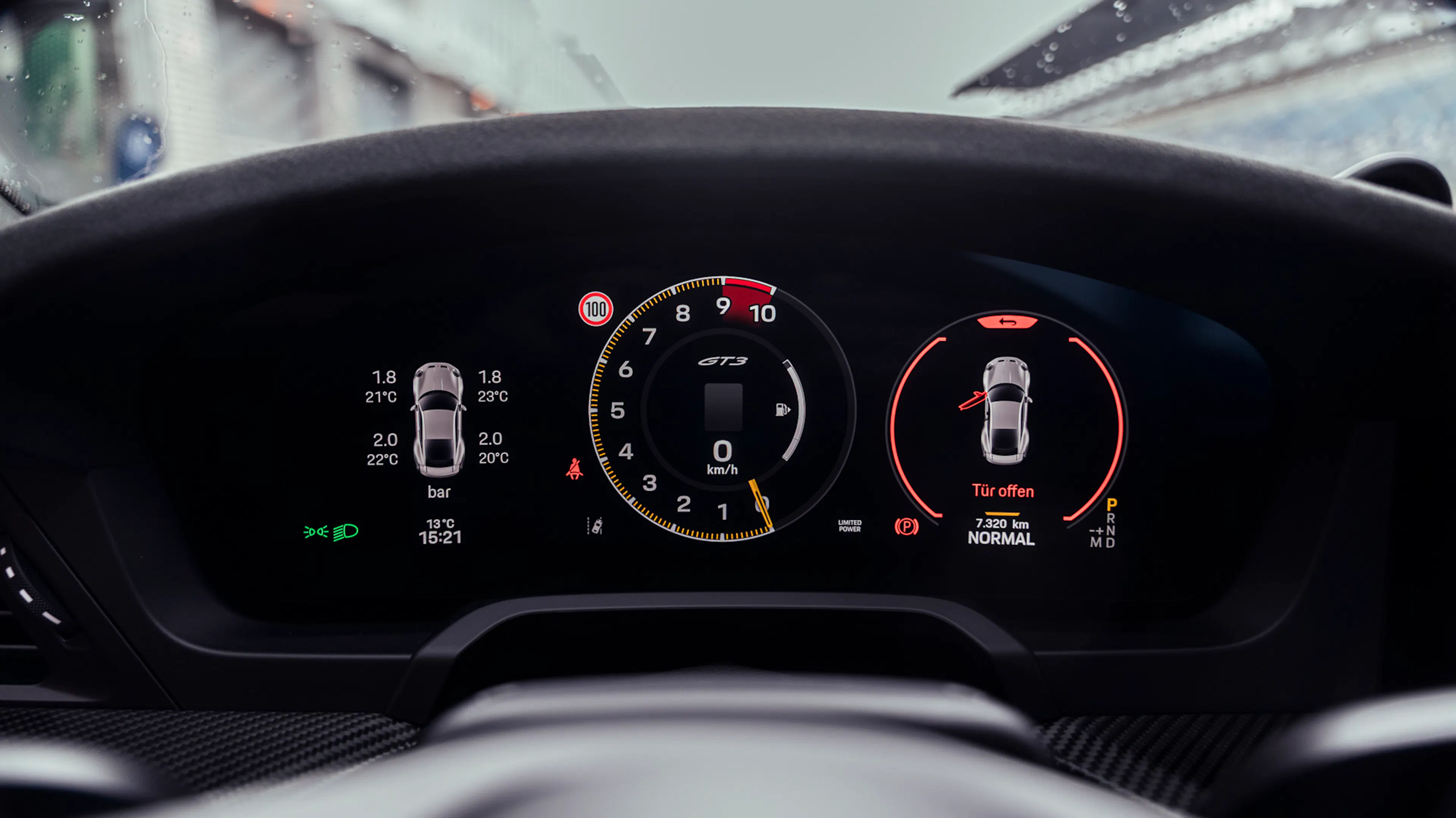 Nahaufnahme des digitalen Kombiinstruments im Porsche 911 GT3 (992.2): zentraler Drehzahlmesser bis 10.000 U/min, Geschwindigkeitsanzeige bei 0 km/h, Reifendruckdaten und Warnhinweis „Tür offen“.