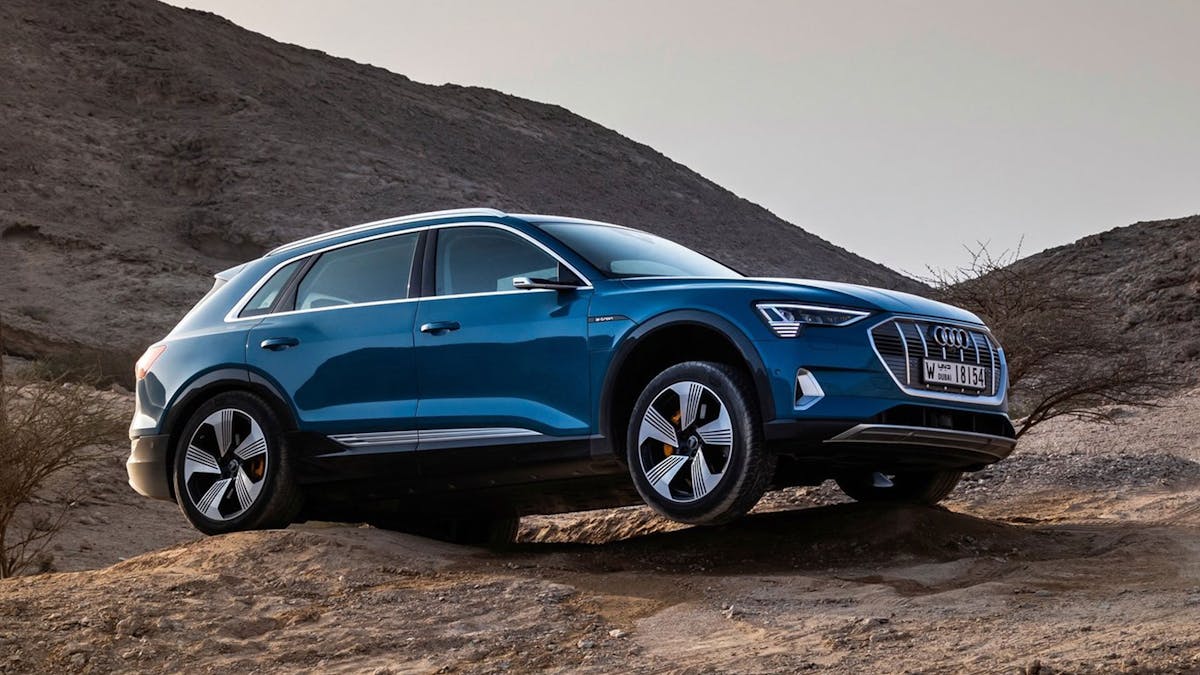 Ein blauer Audi e-tron quattro steht in einer felsigen Landschaft.