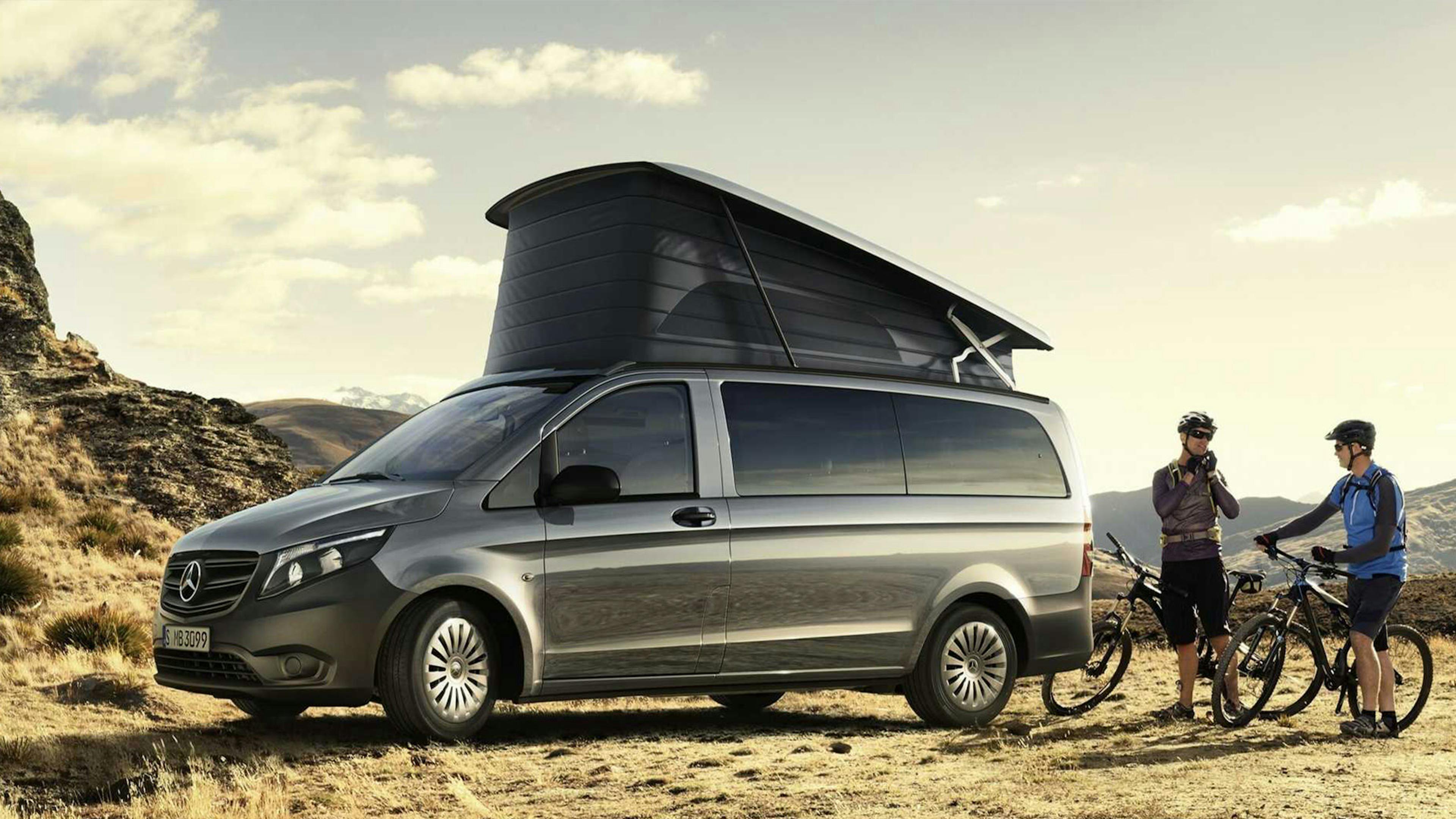 Zwei Fahrradfahrer stehen hinter einem grauen Mercedes-Benz Marco Polo Camper Van.