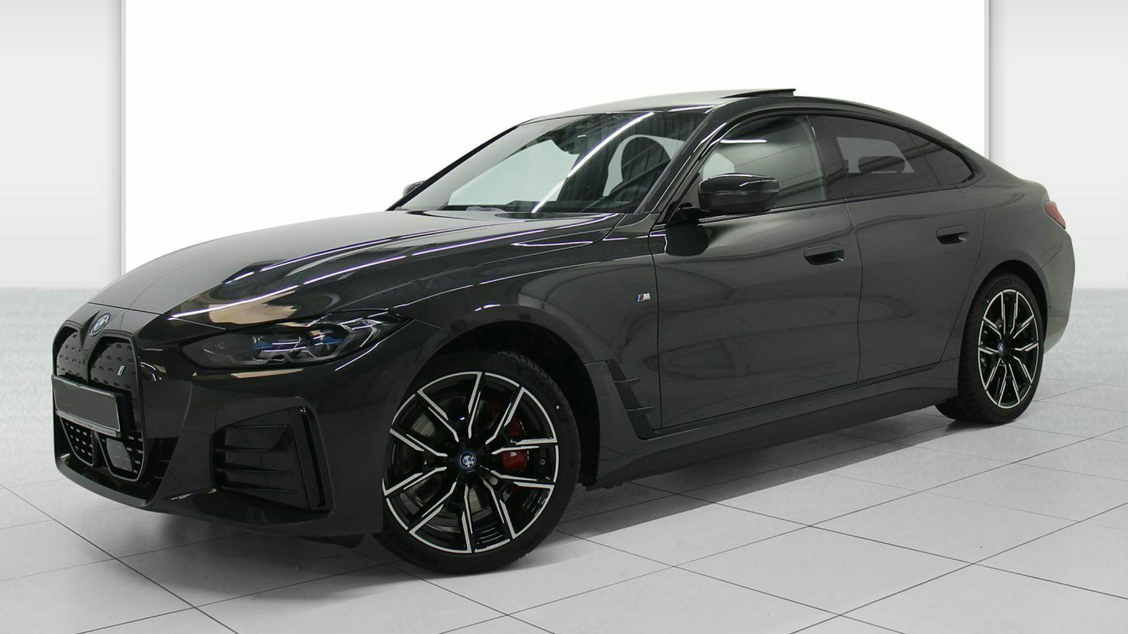 Ein schwarzes BMW-i4-Elektroauto mit Allradantrieb steht in einem hellen Raum.