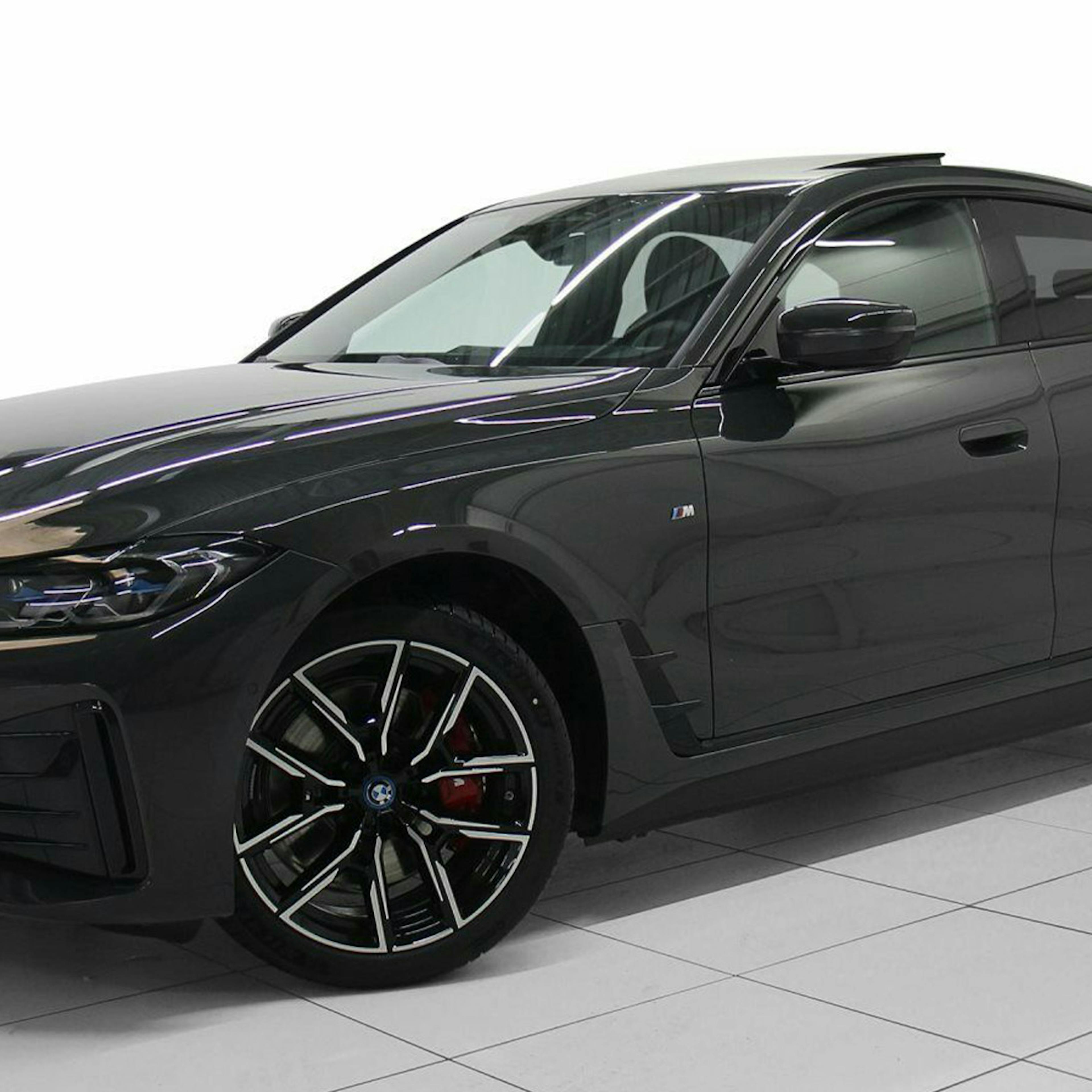 Ein schwarzes BMW-i4-Elektroauto mit Allradantrieb steht in einem hellen Raum.