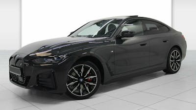 Ein schwarzer BMW i4 mit Anhängerkupplung steht in einem Raum mit weißen Wänden und weißem Boden
