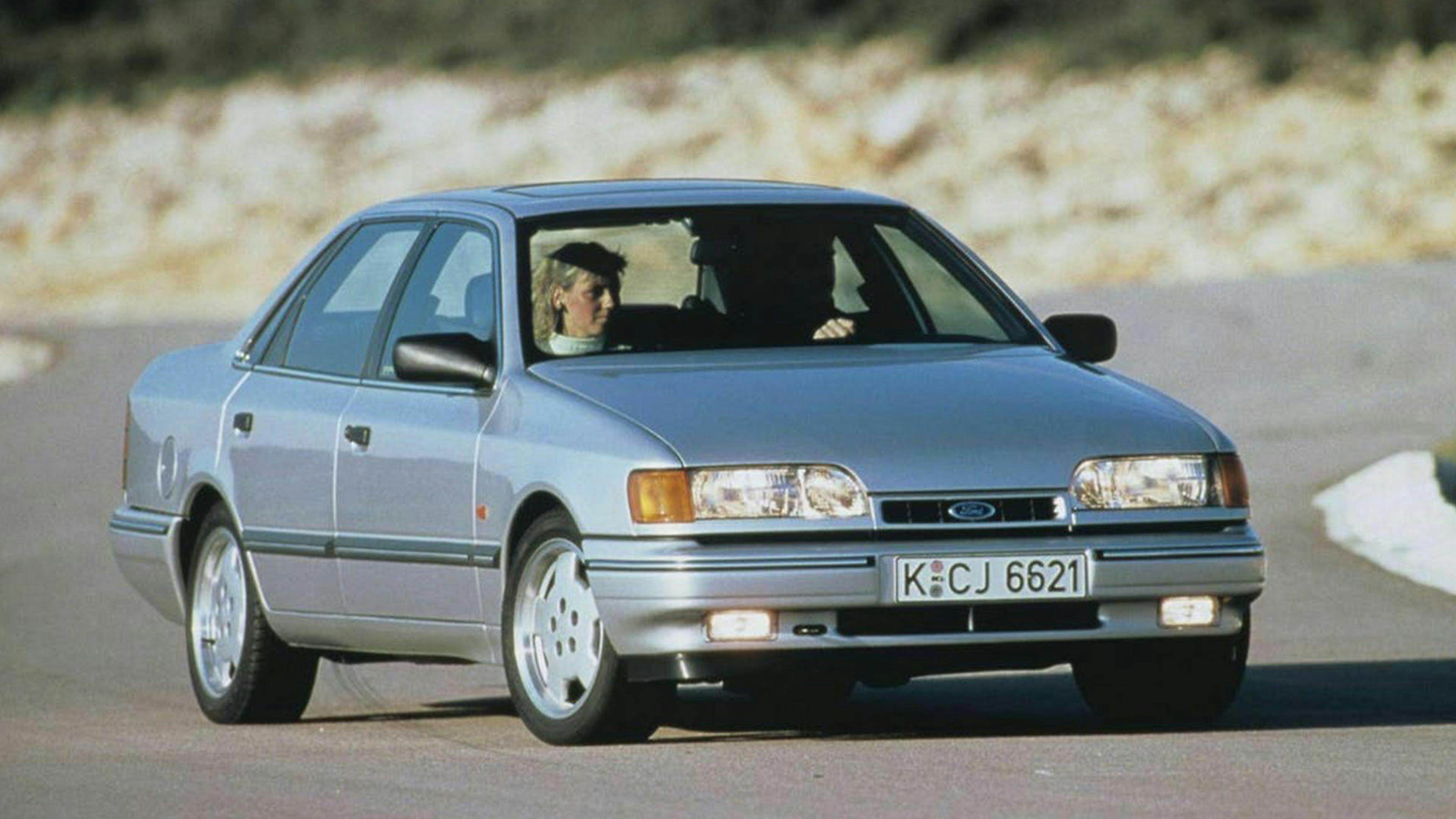 Ein grauer Ford Scorpio fährt eine Straße entlang