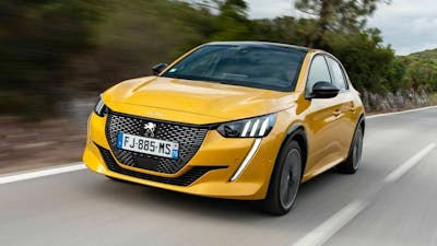 Ein gelber Peugeot 208 mit Automatikgetriebe fährt eine Landstraße entlang.