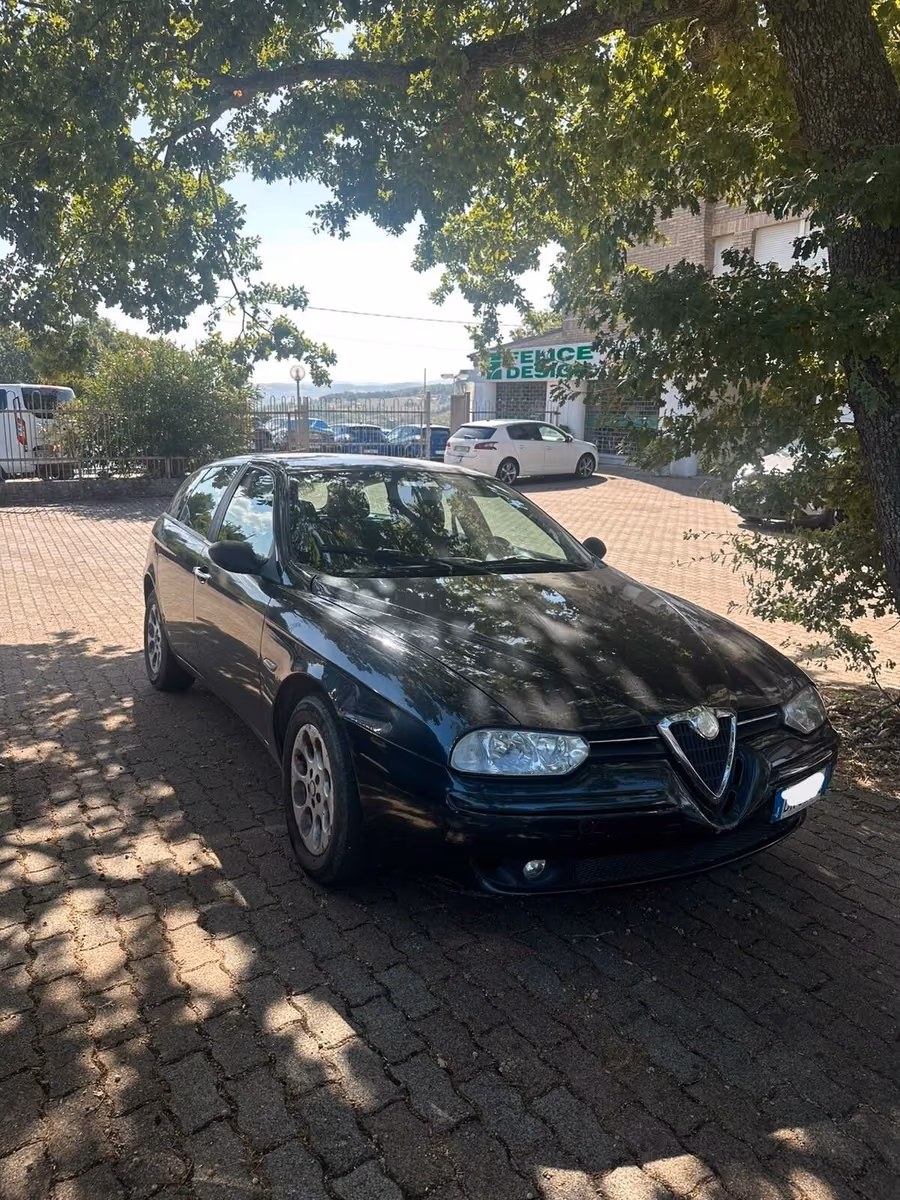 Schwarzer Alfa Romeo 156 steht unter einem Baum