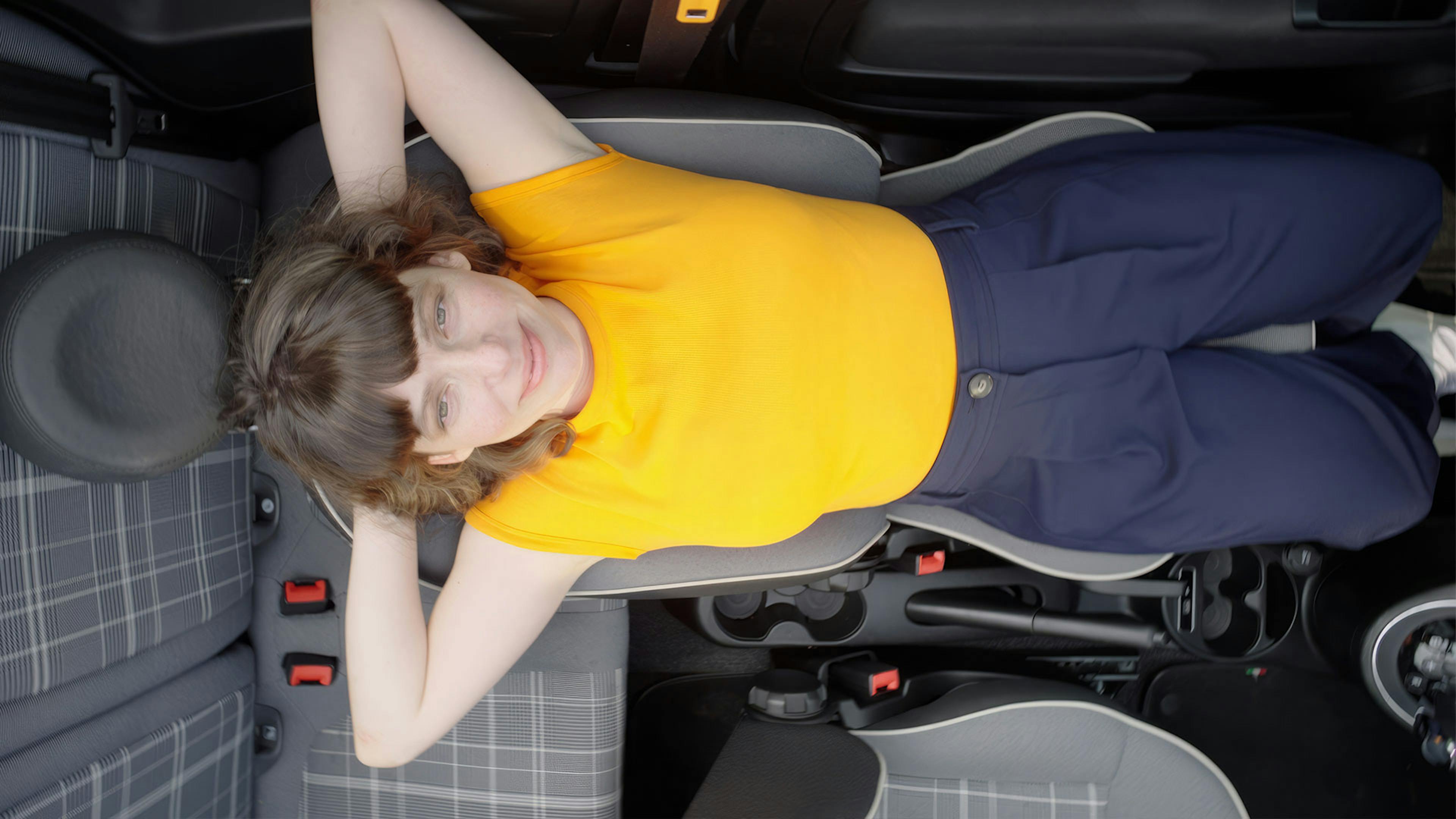 Frau liegt entspannt auf dem Sitz ihres Autos