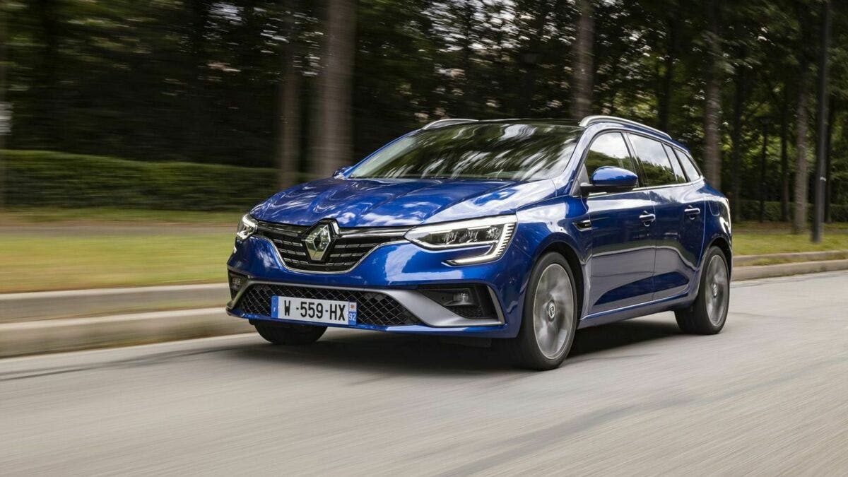 Ein blauer Renault Mégane Grandtour eTech fährt eine Straße entlang an ein paar Bäumen vorbei.