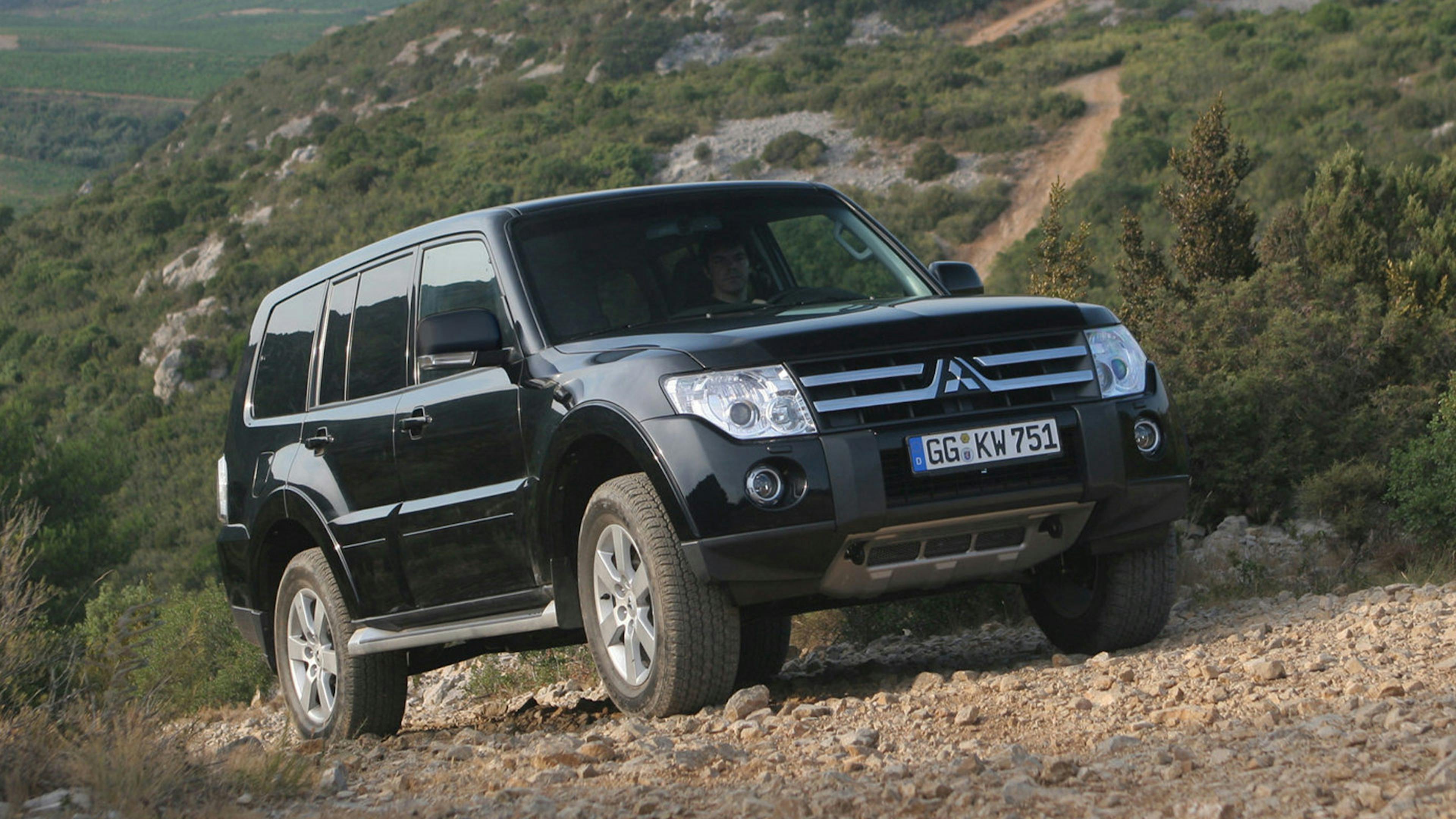 Ein schwarzer Mitsubishi Pajero Geländewagen steht an einem steinigen Hang.