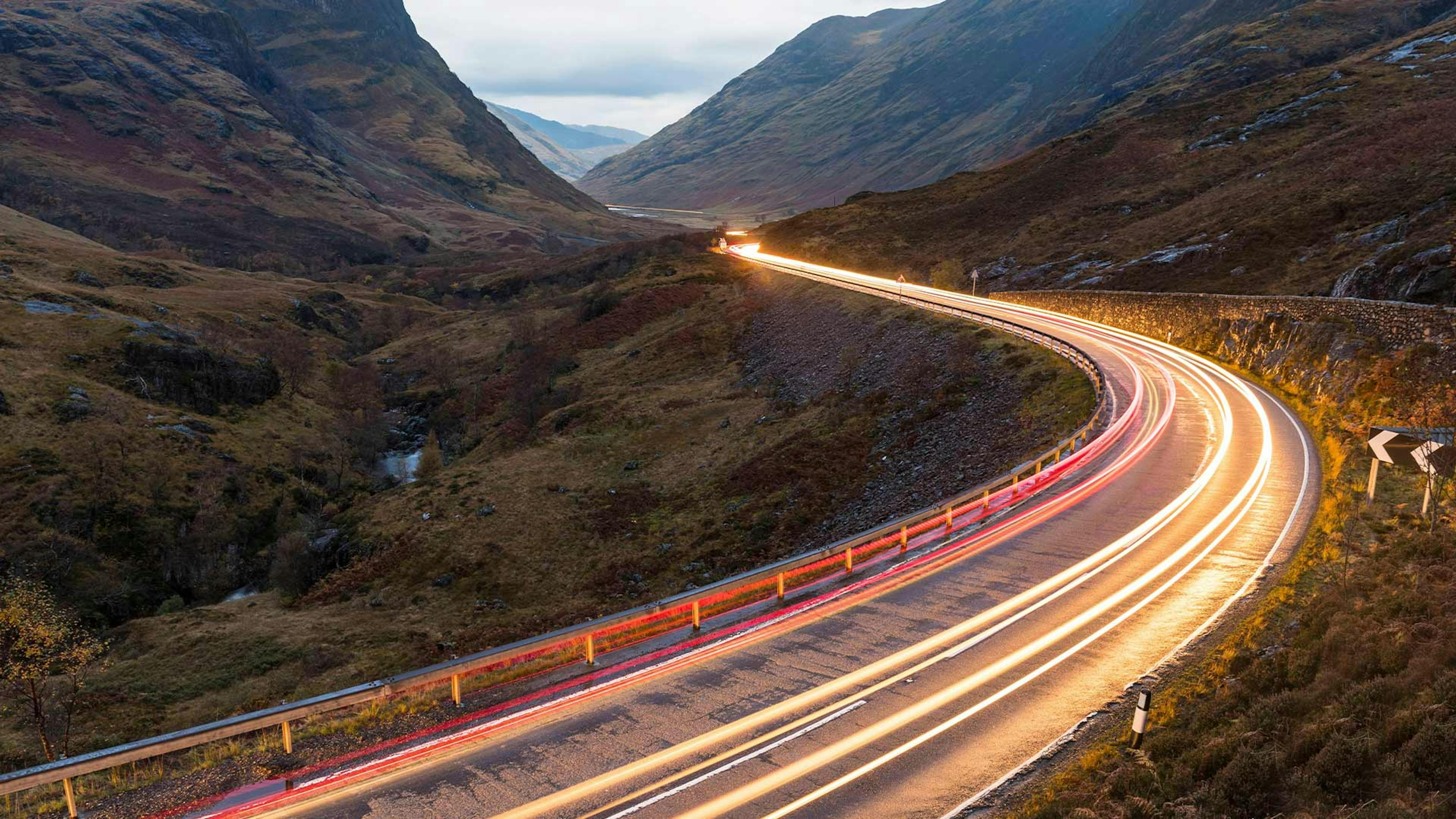 Langzeitbelichtung eines Pkw, der eine kurvige Landstraße entlang fährt