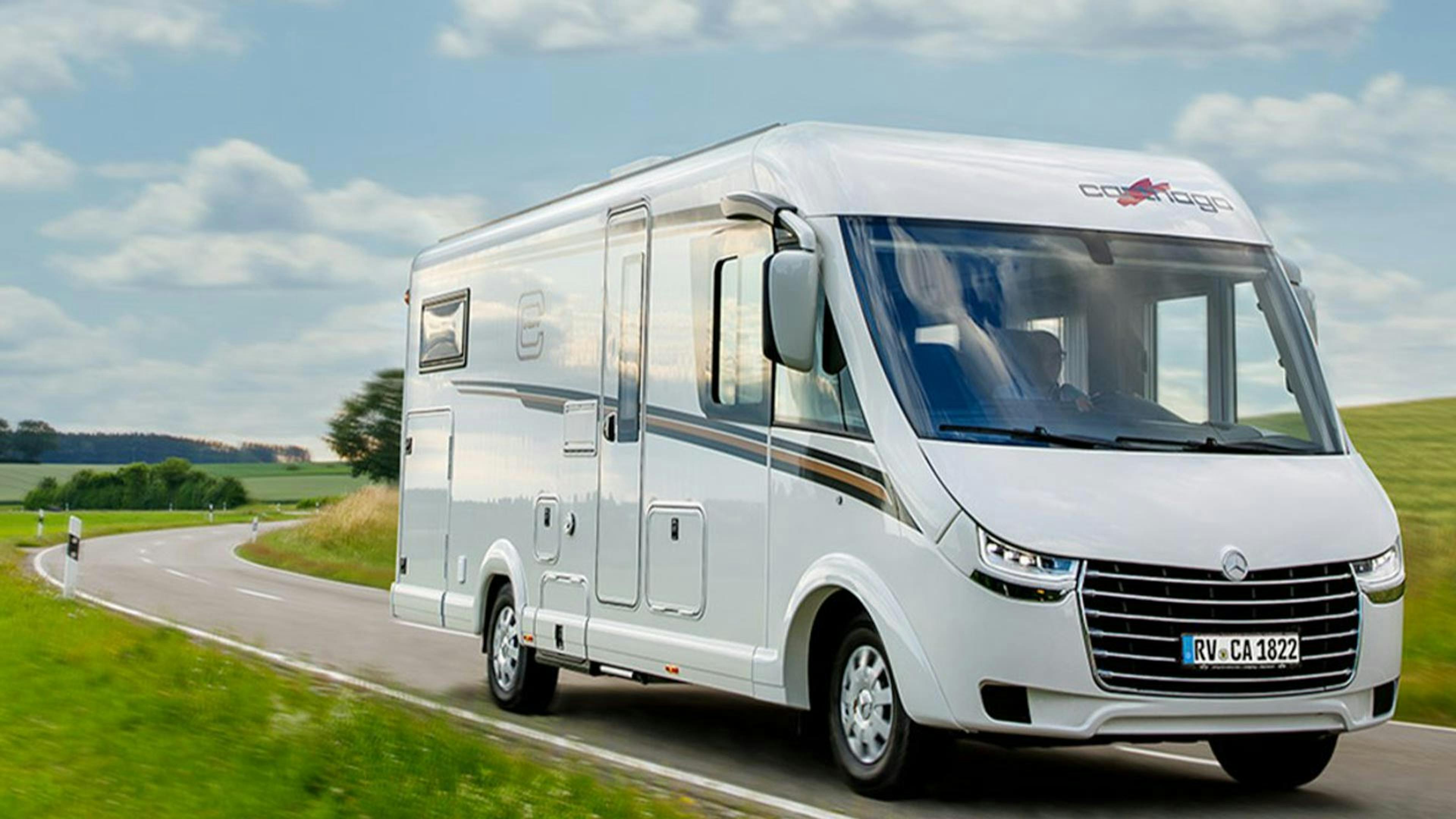 Ein Carthago C-Tourer Wohnmobil fährt eine Landstraße entlang.
