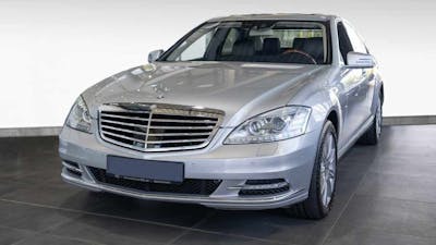 Eine silberne Mercedes-Benz S-Klasse steht vor einer weißen Wand.