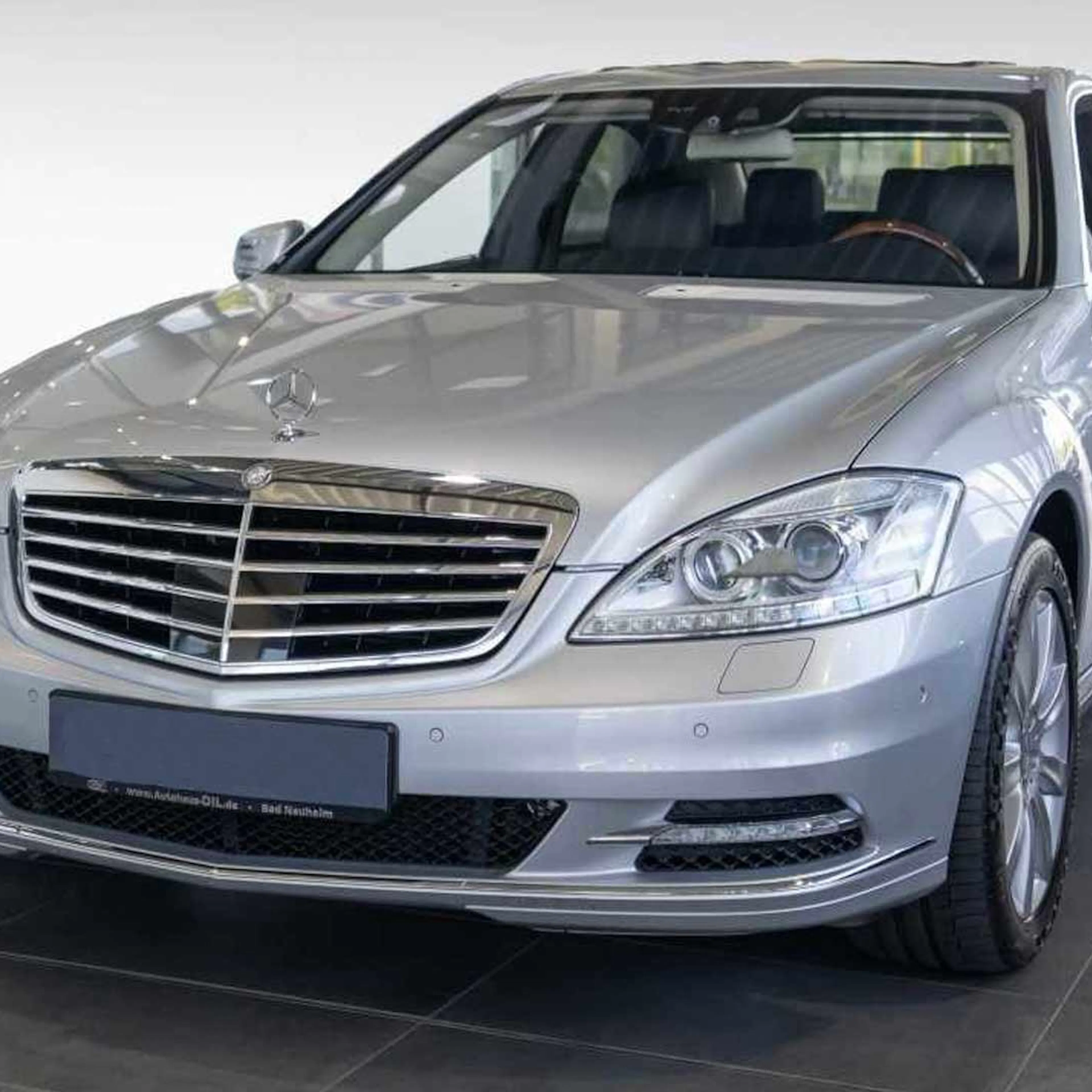 Eine silberne Mercedes-Benz S-Klasse steht vor einer weißen Wand.
