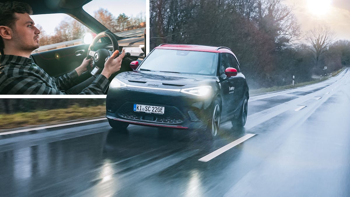 Ein schwarz-roter Smart #1 Brabus fährt auf einer nassen Landstraße.