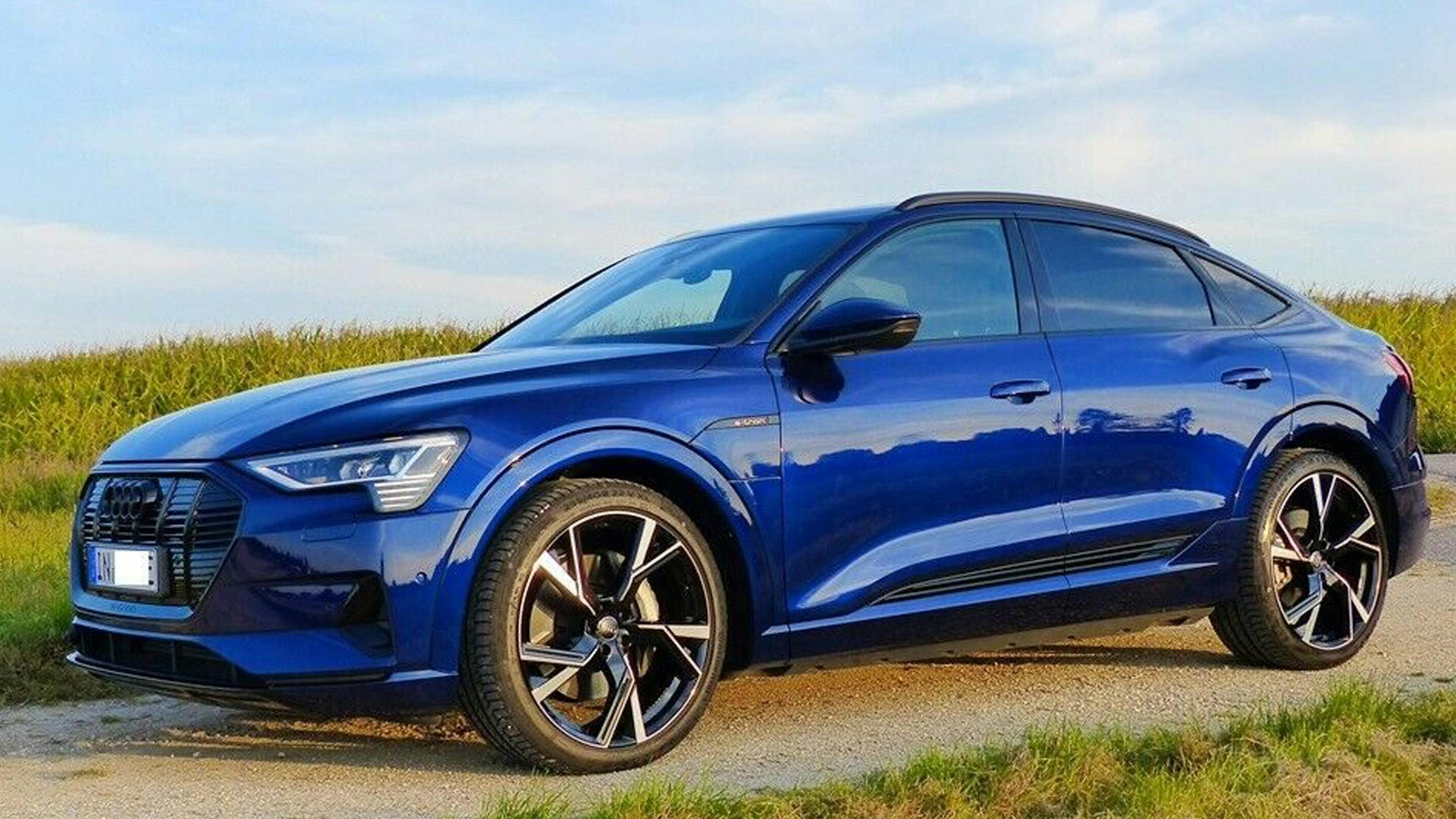 Ein blauer Audi-e-tron-Sportback-Elektroauto mit Allradantrieb steht auf einem Feldweg.