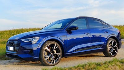 Ein blauer Audi-e-tron-Sportback-Elektroauto mit Allradantrieb steht auf einem Feldweg.