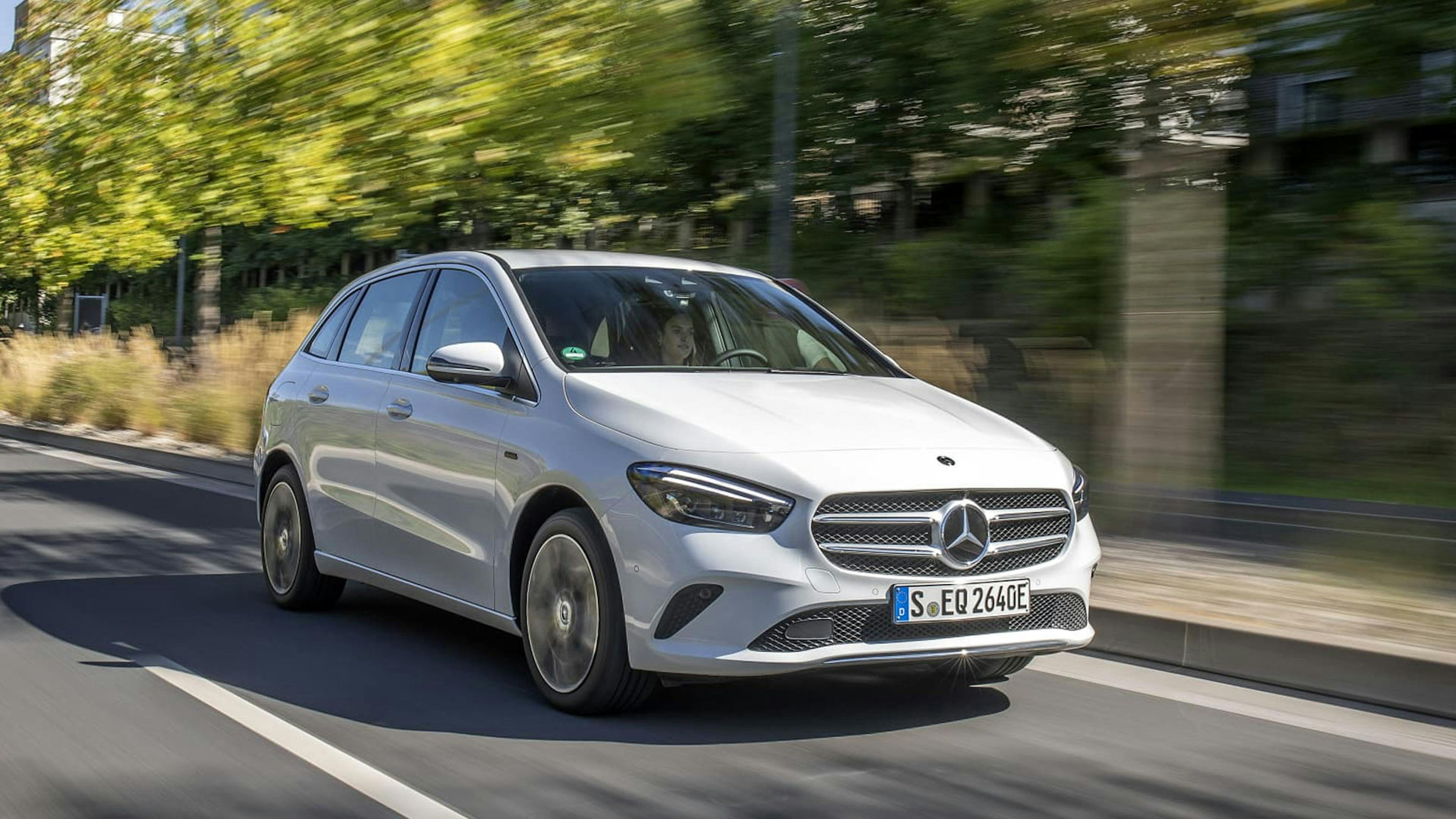 Ein weißer Mercedes B250e mit Hybrid-Antrieb fährt eine Straße entlang.