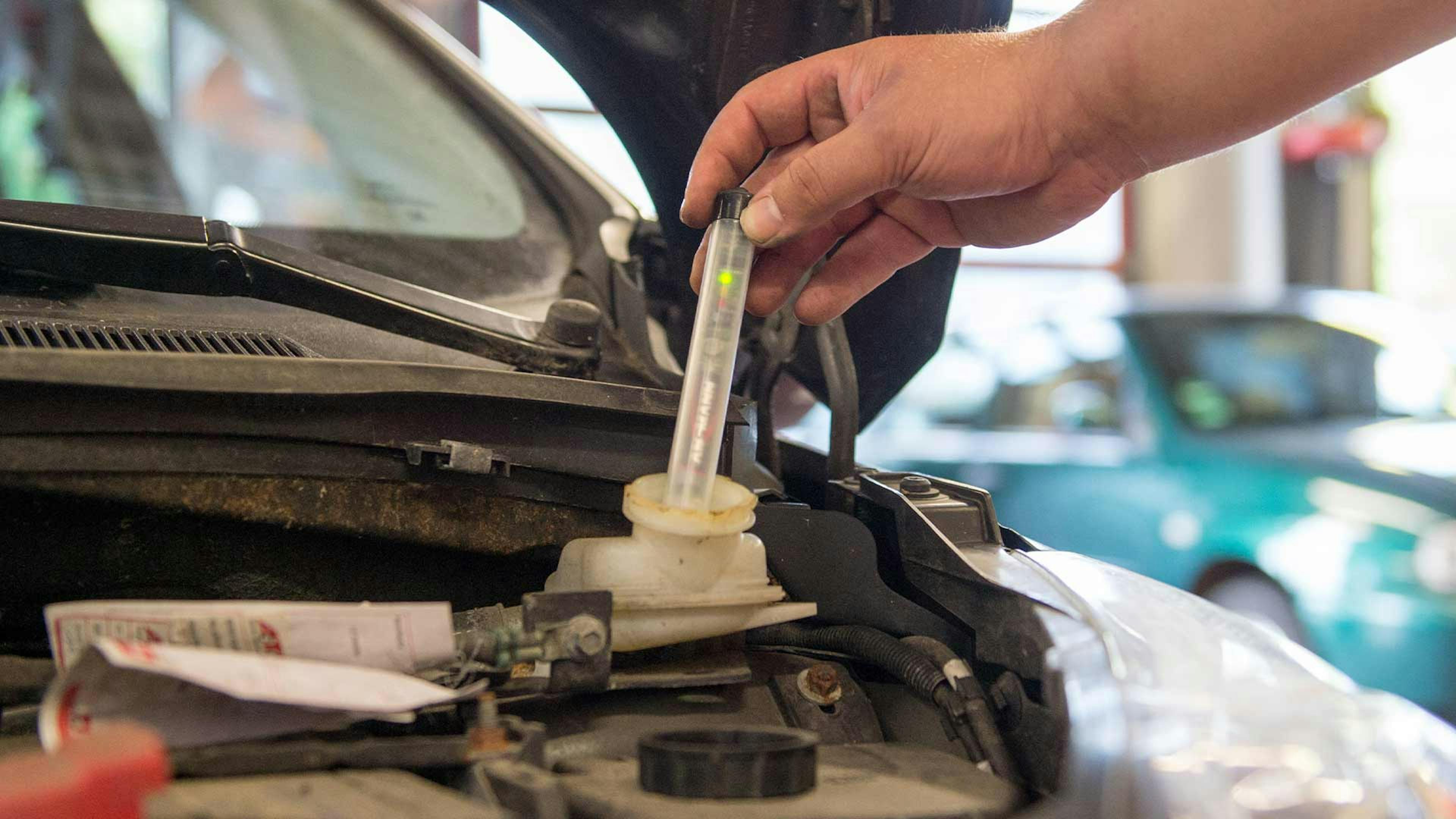 Ein Kfz-Mechaniker prüft die Bremsflüssigkeit eines Autos.