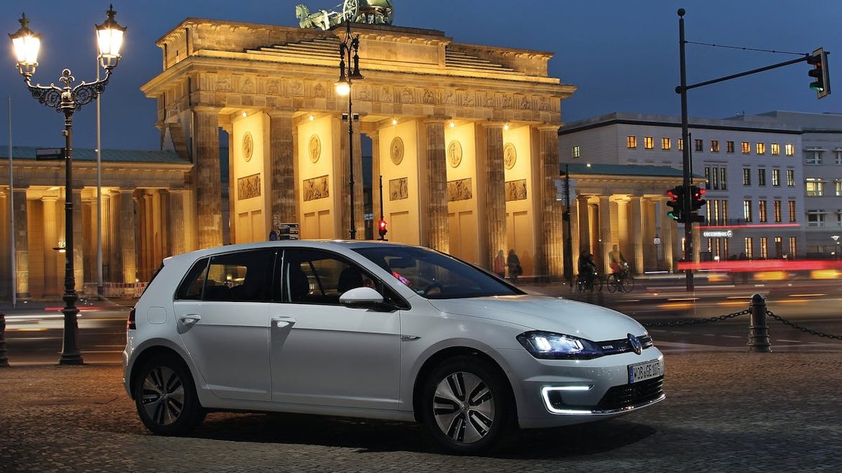 Ein weißer VW e-Golf steht abends vor dem Brandenburger Tor. 