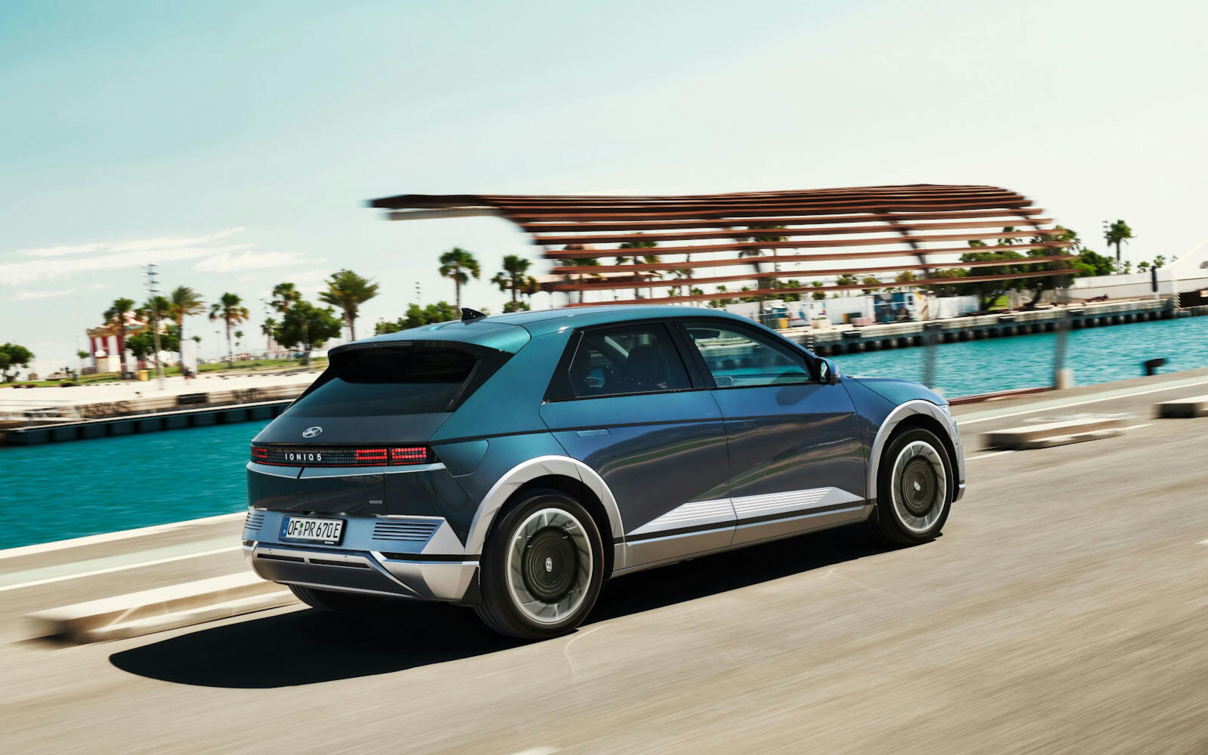 Ein blauer Hyundai Ioniq 5 fährt an einem Kanal entlang.