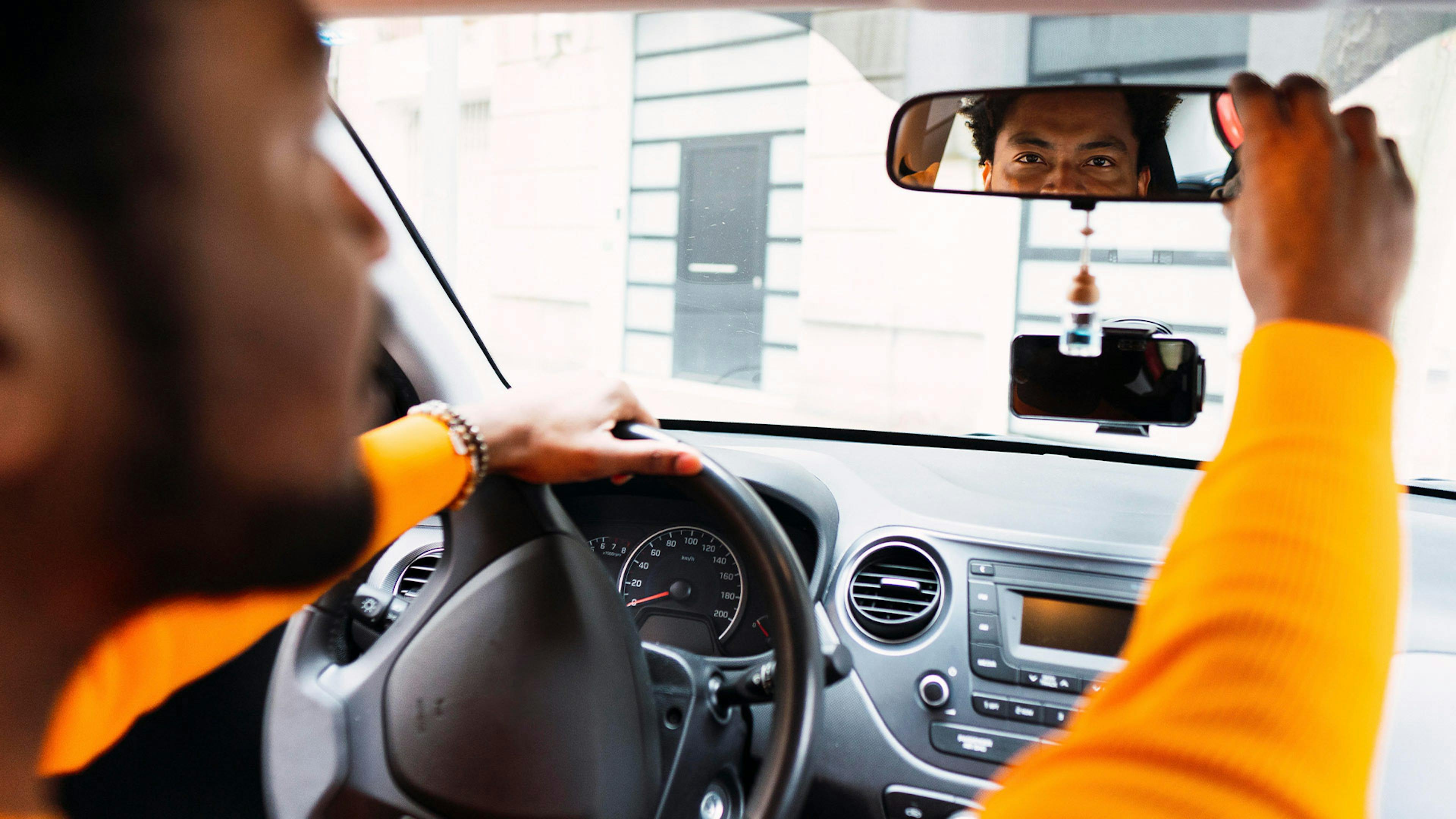 Ein Mann stellt den Innenspiegel eines Pkw ein.