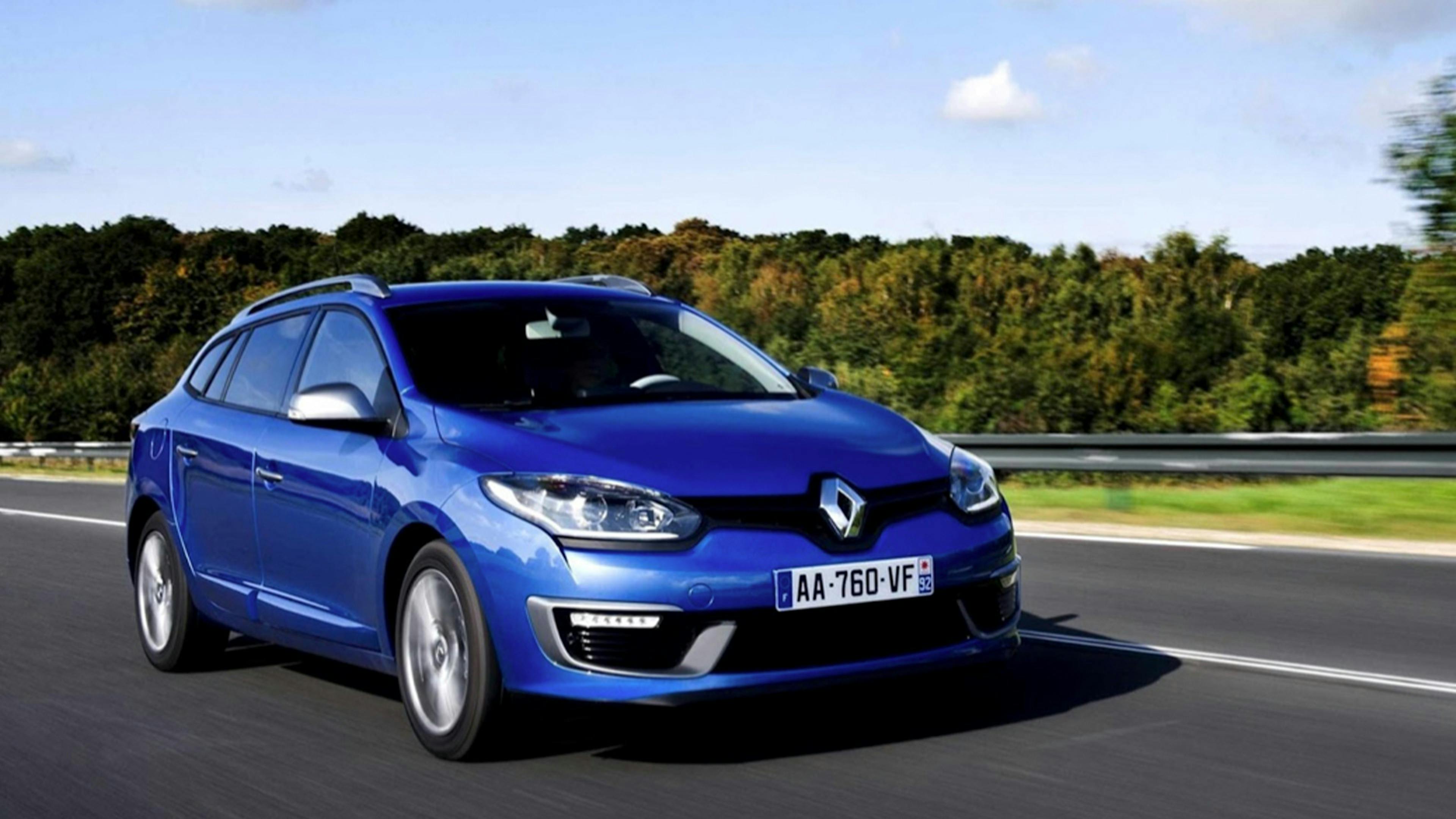 Ein blauer Renault Mégane III Grandtour fährt eine Landstraße entlang.
