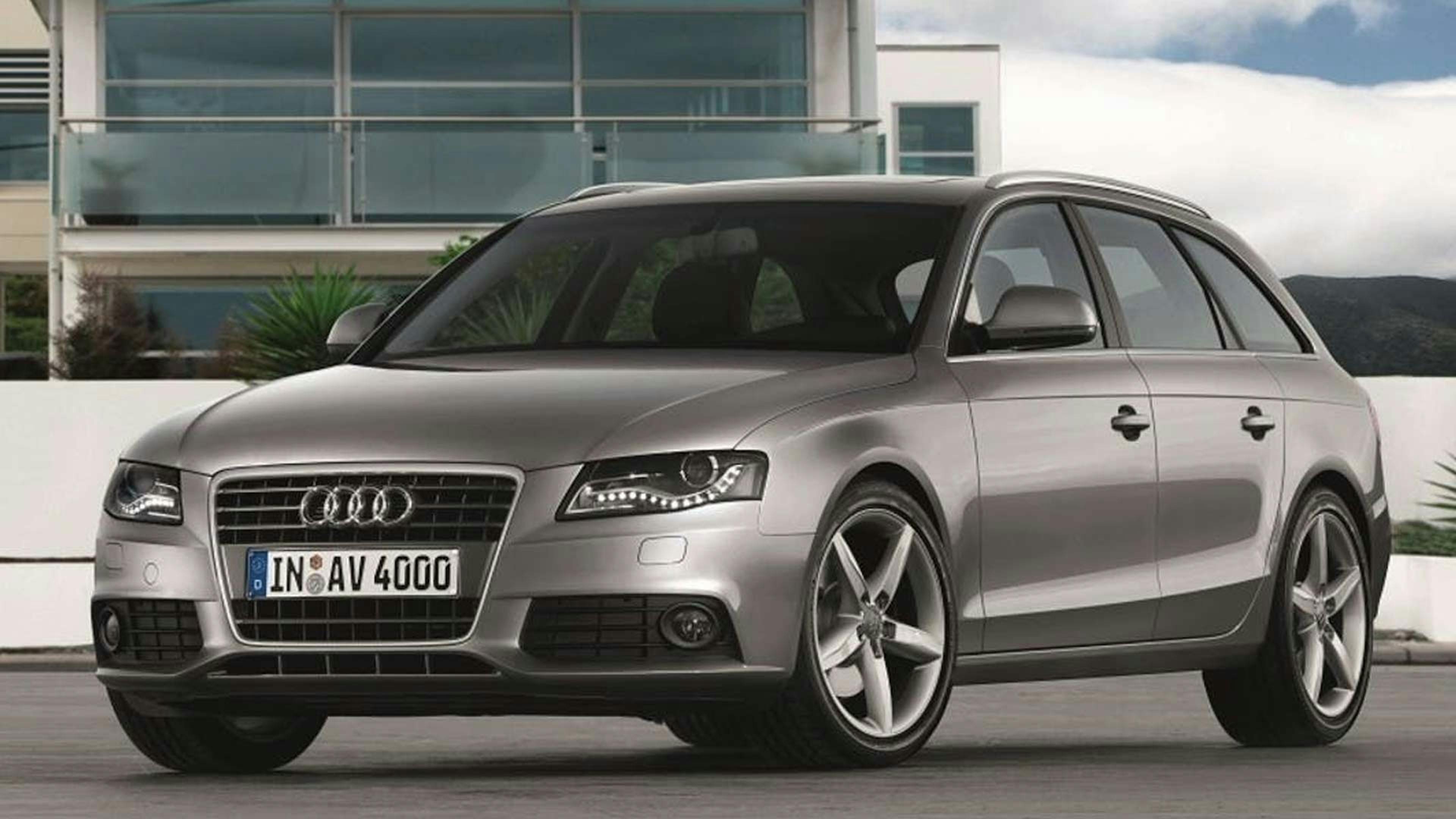 Ein silberner Audi A4 Avant B8 Kombi steht vor einem weißen Gebäude.